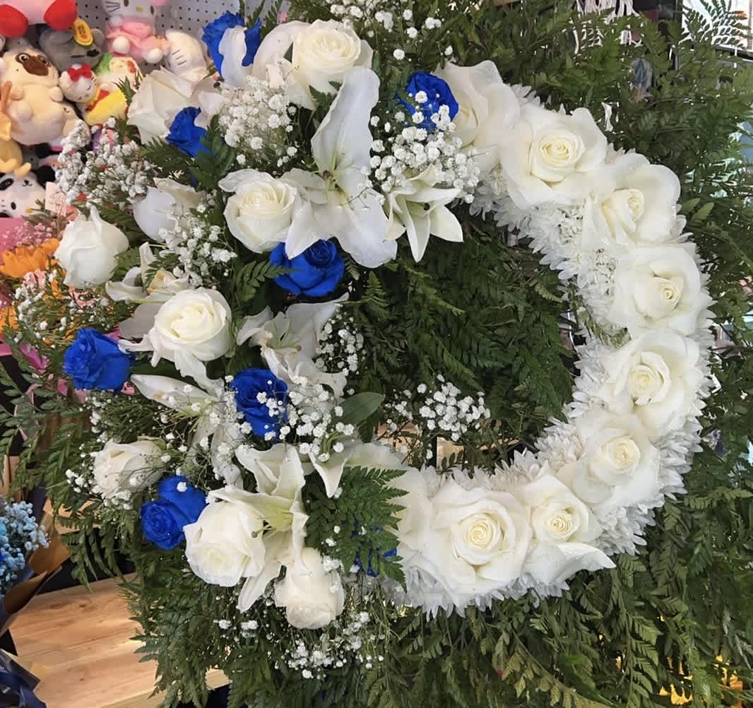 Large floral wreath of white roses, lilies, and blue roses