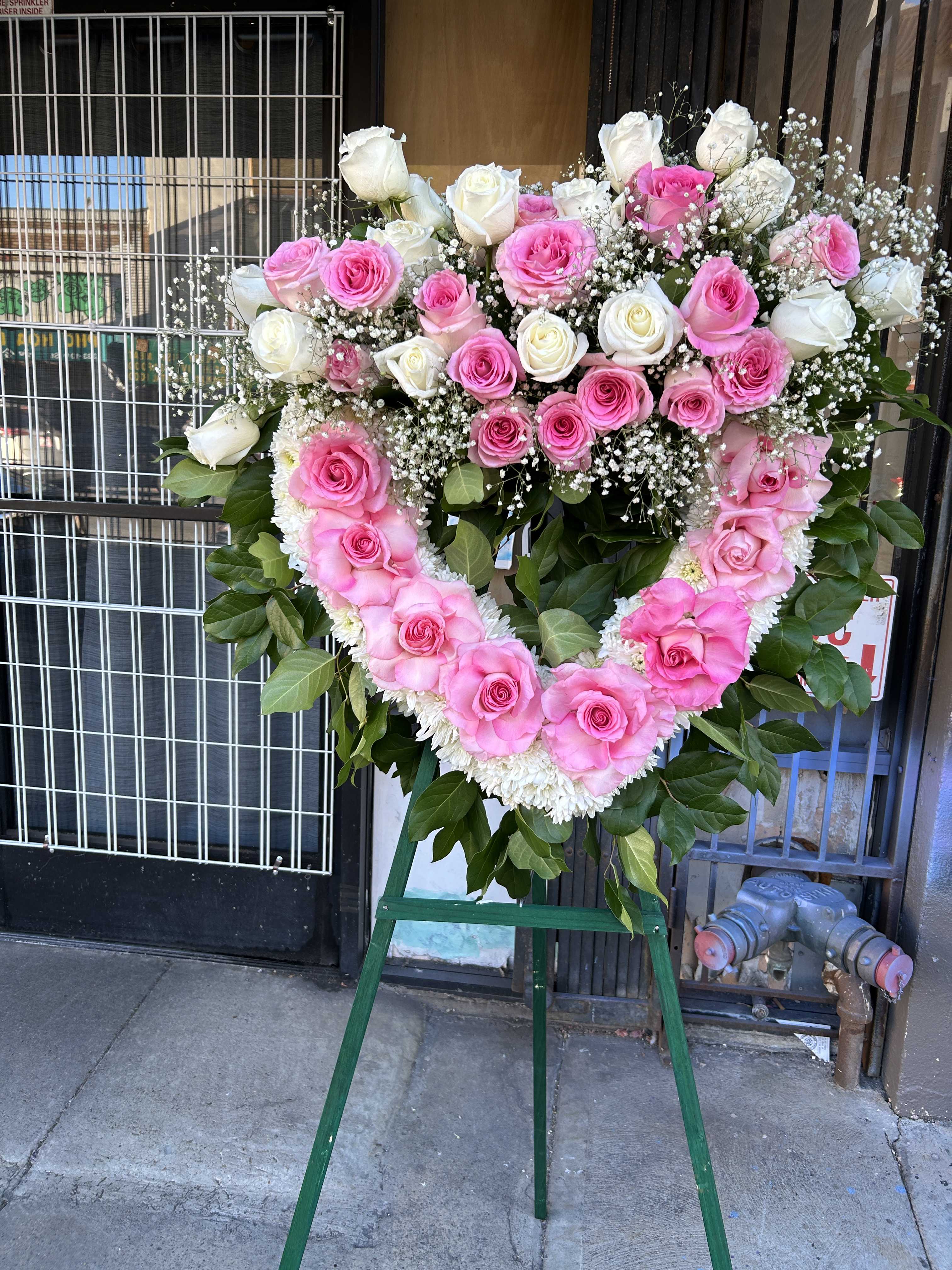 Heart-shaped pink and white rose standing spray on an easel