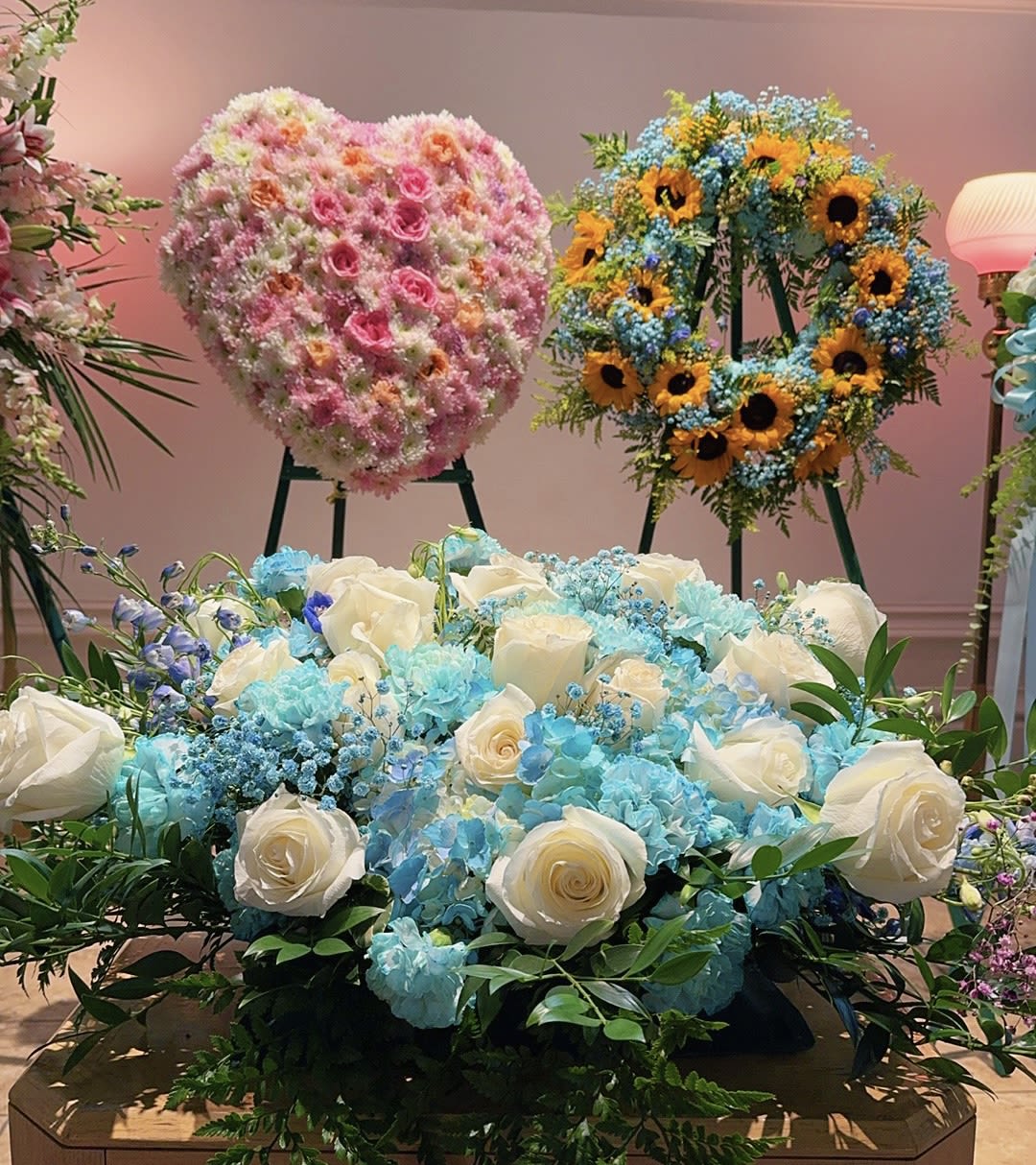 Large floral display with white roses and blue hydrangeas in front of wreaths