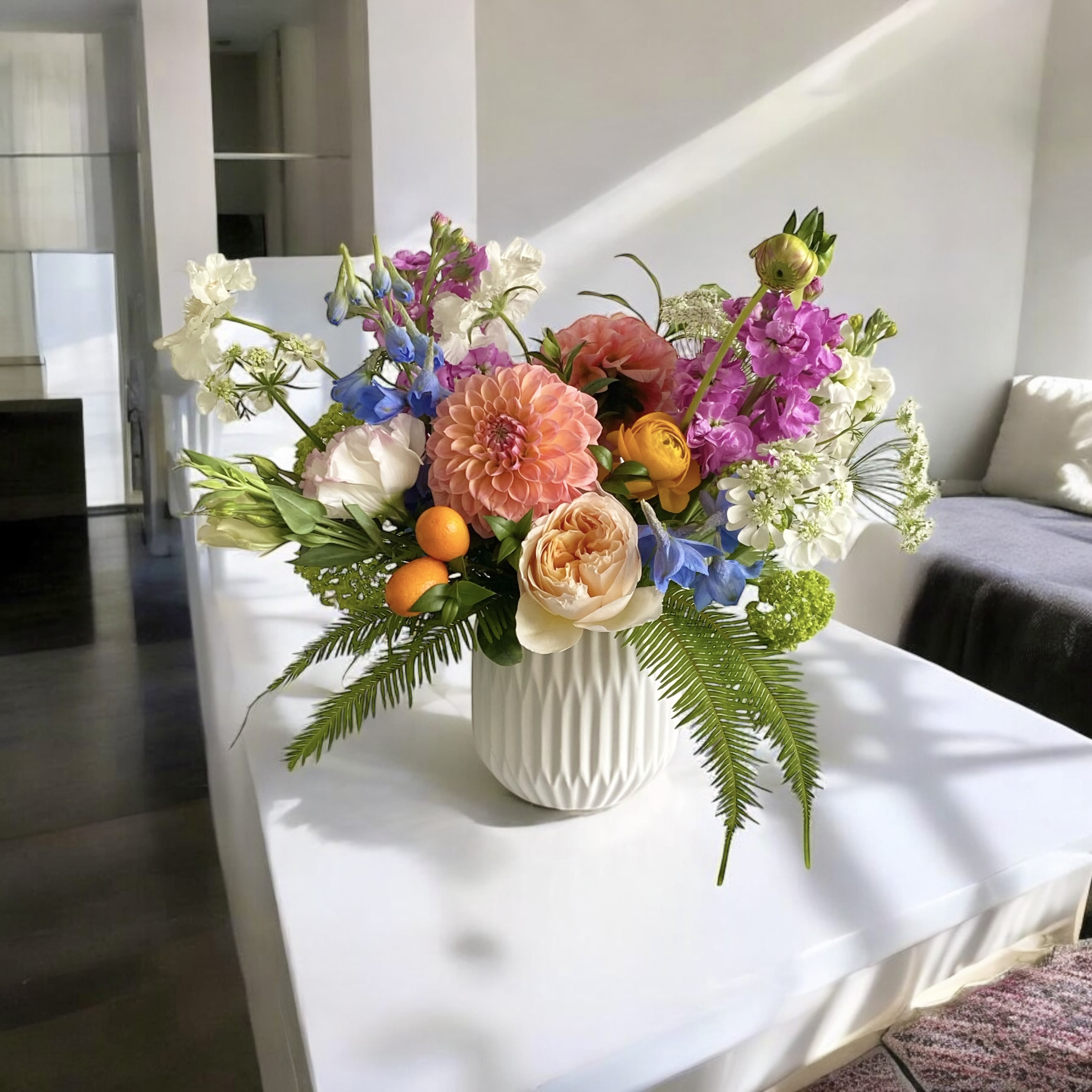 Colorful mixed flower arrangement in a white vase on a table