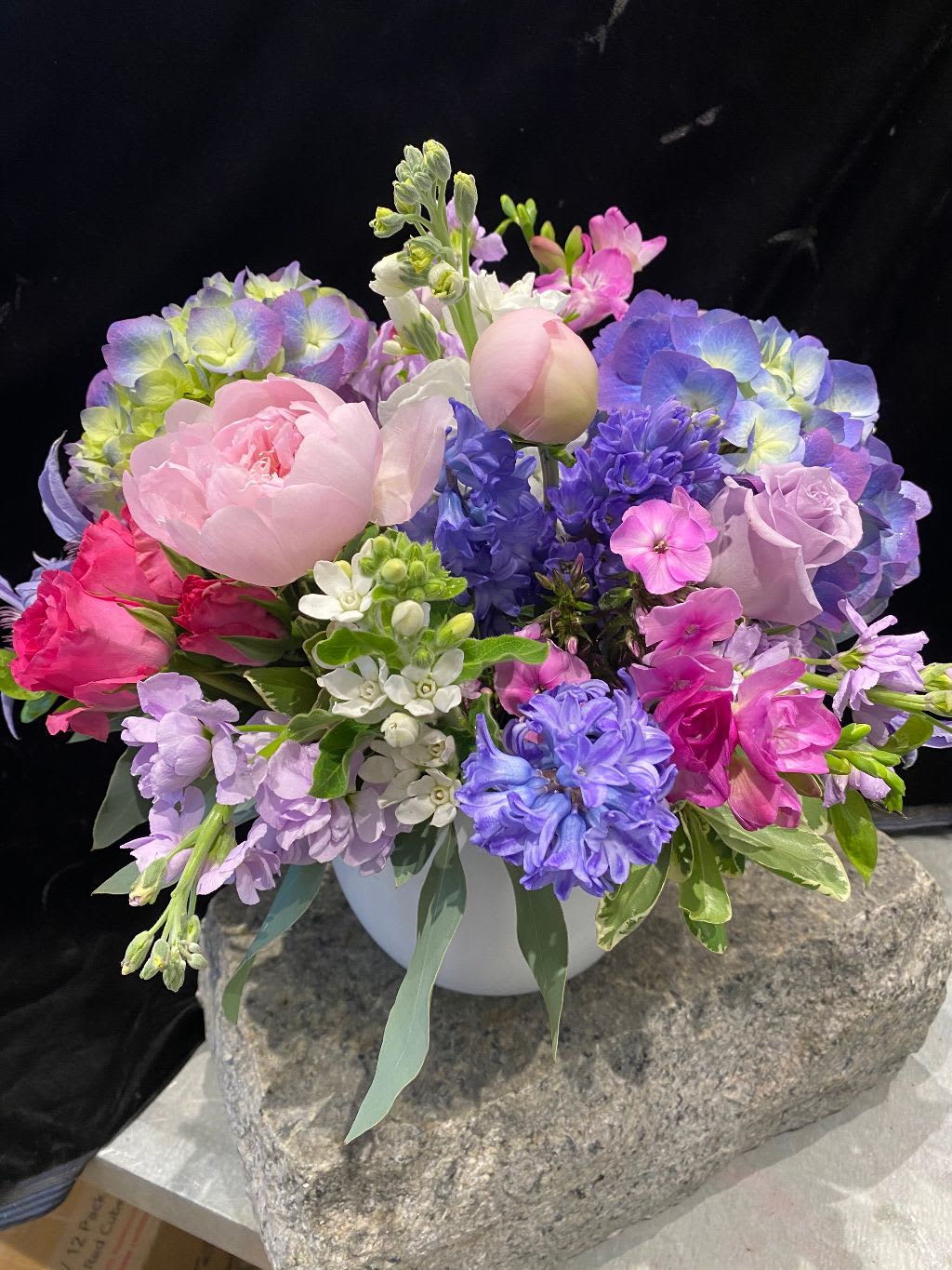 Pastel bouquet of peonies, hydrangeas, and hyacinths in a white vase