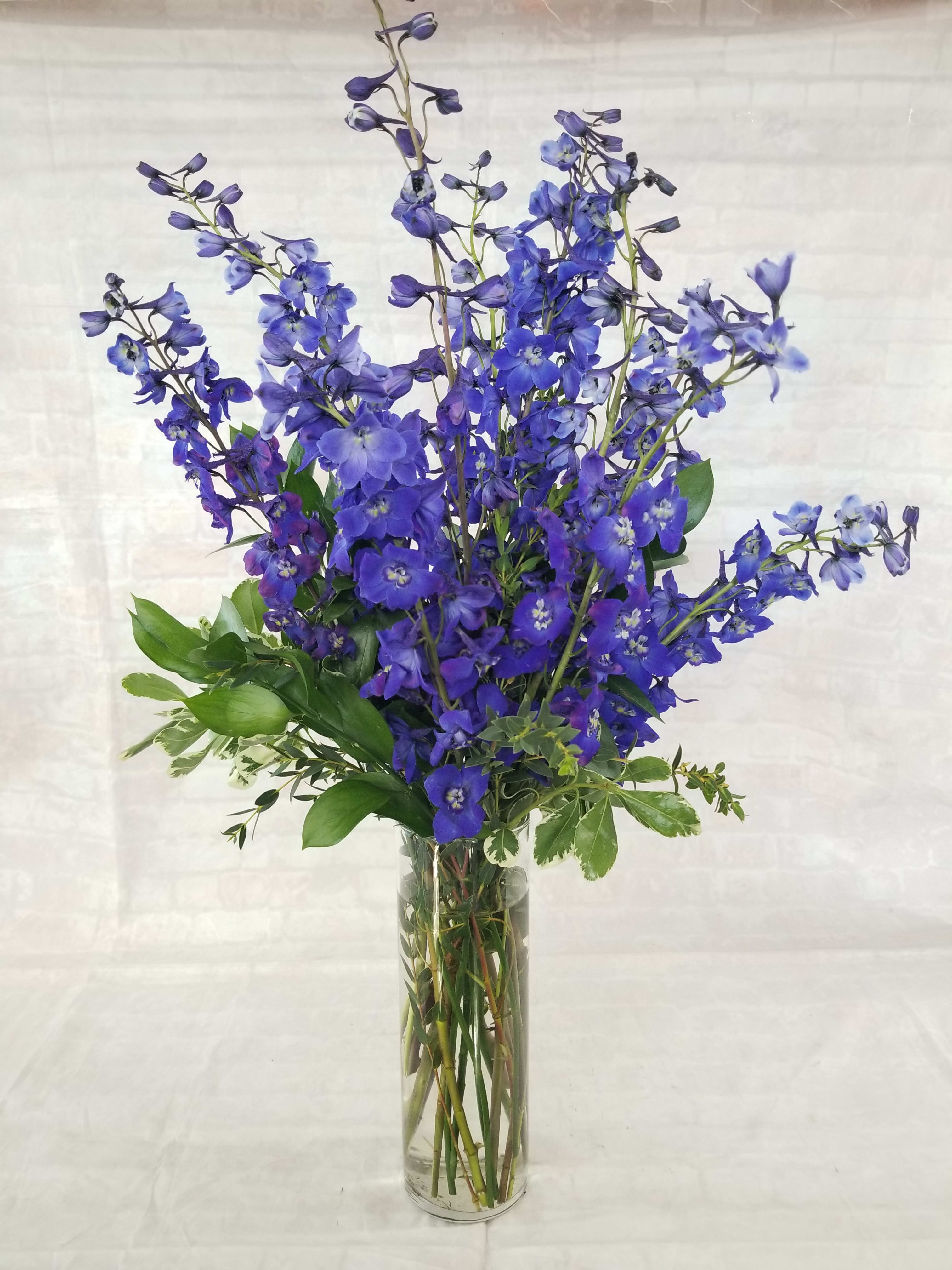 Tall blue delphinium arrangement in a clear glass vase