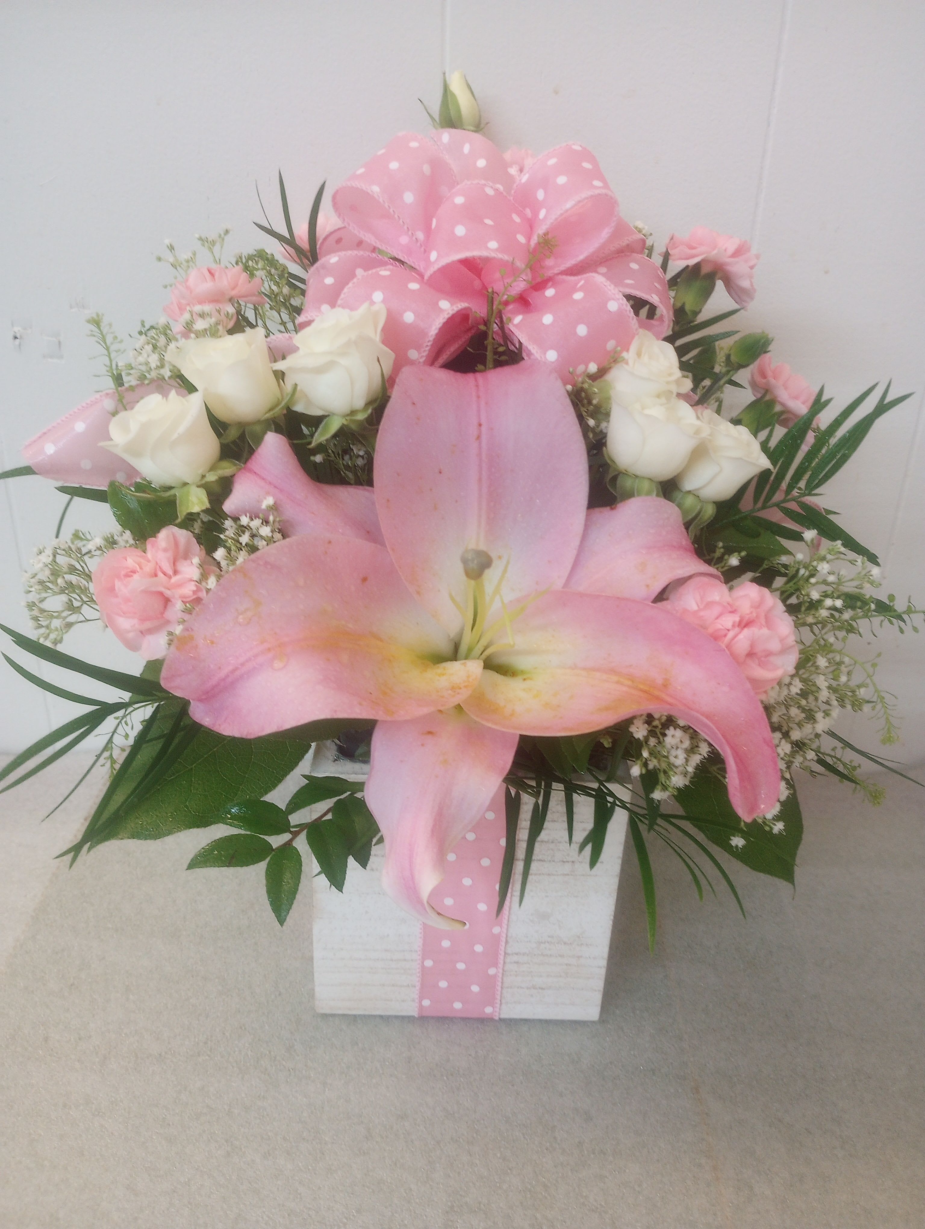 My Dear - The composition-designed to make the person you're thinking of feel cherished-pairs that dramatic lily with clusters of white roses and soft pink carnations so the focal bloom reads bold without overpowering the overall softness.
