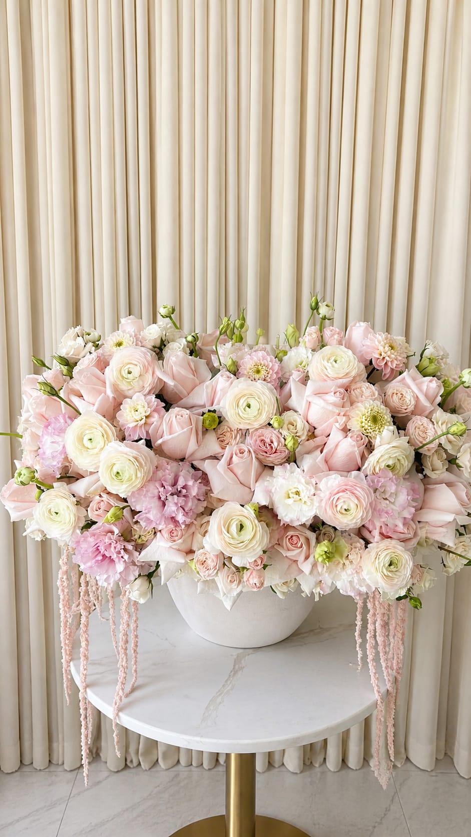 Whisper of Pink - Soft, romantic, and delicately refined, Whisper of Pink is a graceful composition of blush and pastel pink blooms designed to evoke a sense of calm beauty. Featuring a curated mix of dahlias, roses, ranunculus, and cascading amaranthus, this arrangement creates a lush, airy silhouette with gentle movement and rich texture throughout.  The soft pink palette brings timeless elegance, while the flowing amaranthus adds a subtle, cascading touch for added dimension. Each bloom is thoughtfully placed to achieve fullness, balance, and a natural garden-inspired feel.  Perfect for meaningful gifting, celebrations, or elevating everyday spaces, Whisper of Pink captures the essence of softness and quiet luxury.
