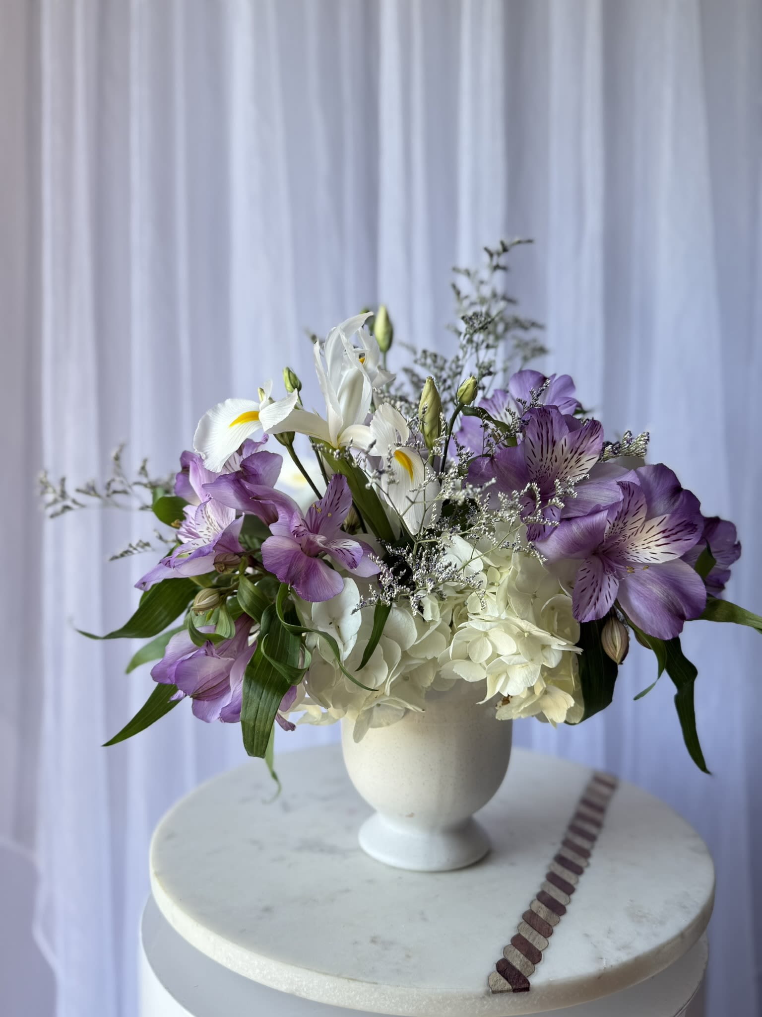 Lavander whisper - A delicate composition that speaks in soft tones and graceful textures. Lavender Whisper blends dreamy lavender alstroemeria with crisp white hydrangea and elegant iris, creating a balanced harmony of romance and freshness. Airy accents and natural greenery add movement and lightness, making this arrangement feel effortlessly refined.