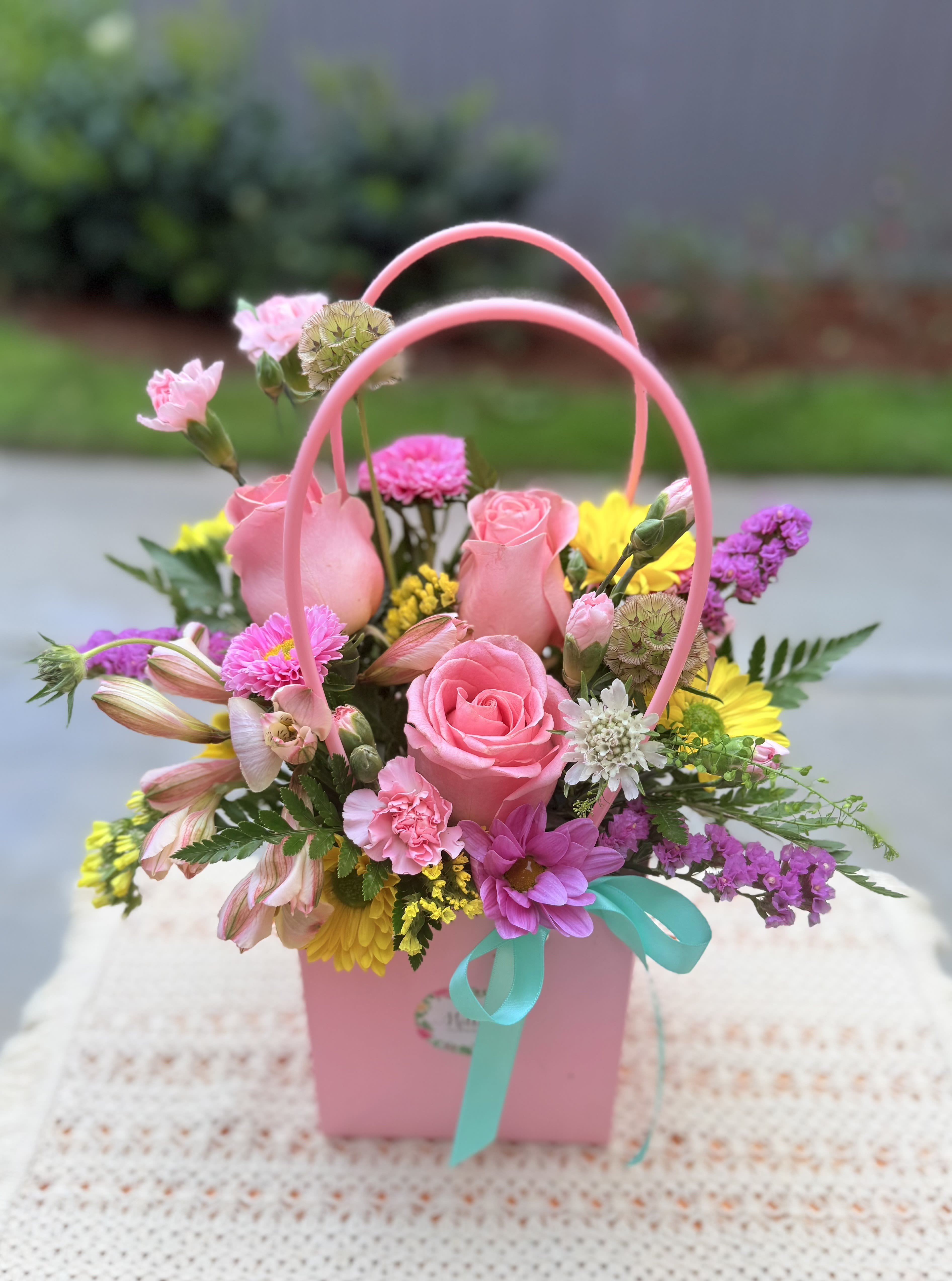 “ Jessica “ Flower Bag - A stunning floral design featuring premium flowers in soft pink and spring tones: Ecuadorian roses, daisies, fancy statice, mini carnations, delicate alstromerias, seasonal filler flowers and seasonal foliage. This charming arrangement is perfect for Mother’s Day, birthdays, just because, thinking of you, best friend's day or simply showing  you care. Standard size.  Garden style, one side arrangement. 