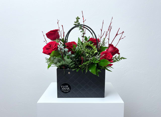 Crimson Elegance Box - A sophisticated arrangement of luxurious red roses paired with fresh greenery and seasonal accents, beautifully presented in a modern signature Floramar box with handle. Crimson Elegance Box is designed to make a bold and timeless statement—perfect for expressing deep love, admiration, or appreciation.