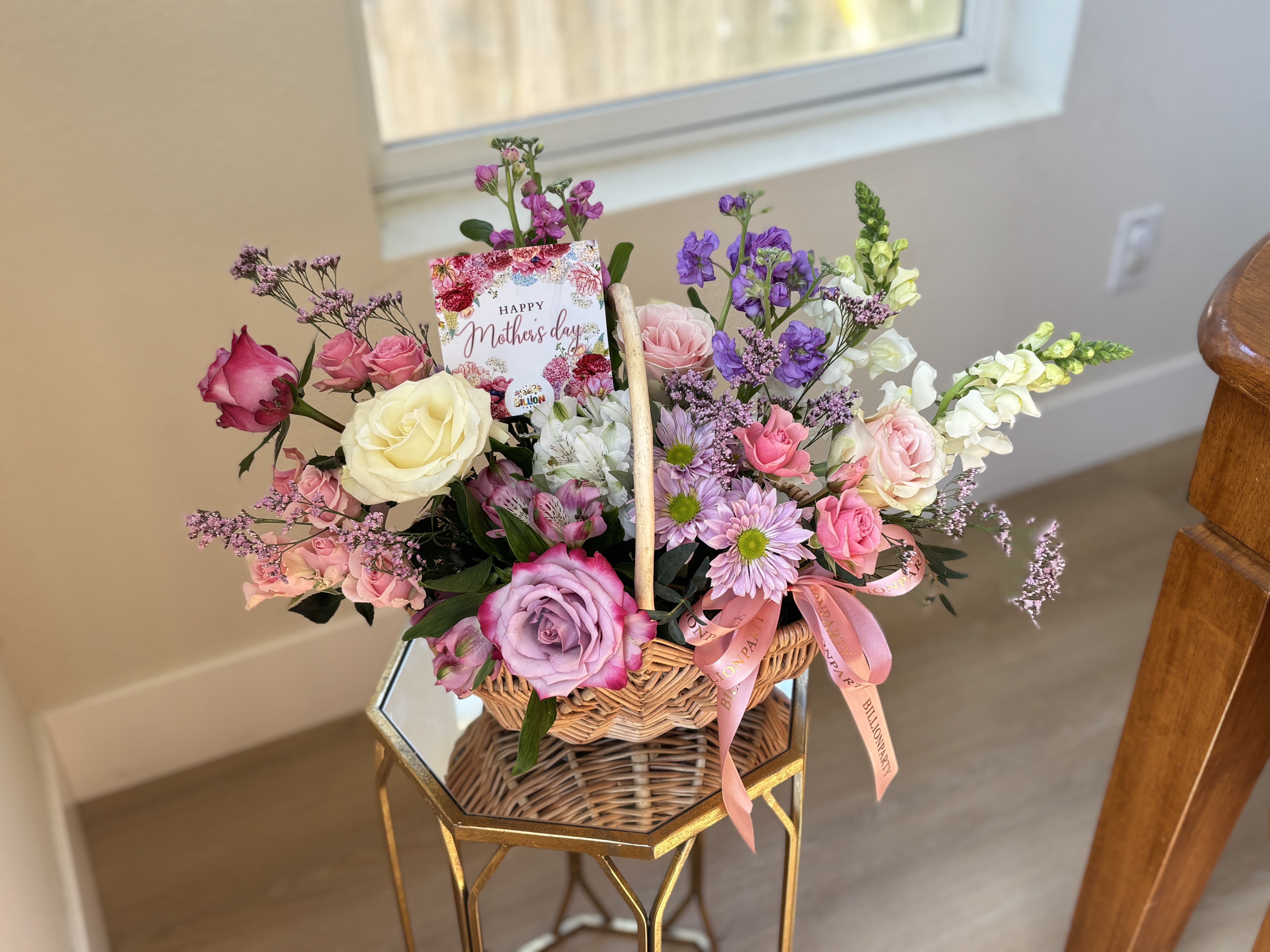 Basket arrangement of roses, daisies, and snapdragons with a Mother's Day card