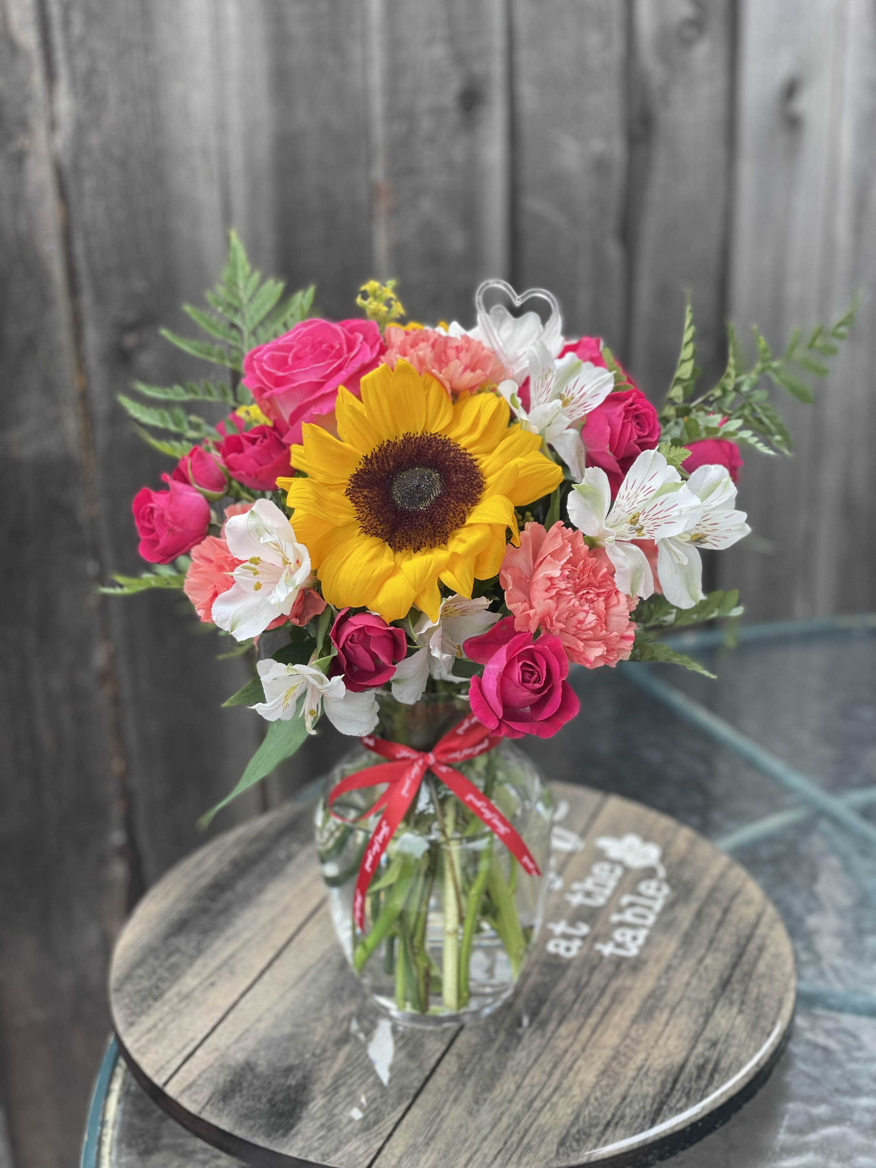 Sunflower and pink rose bouquet in a glass vase