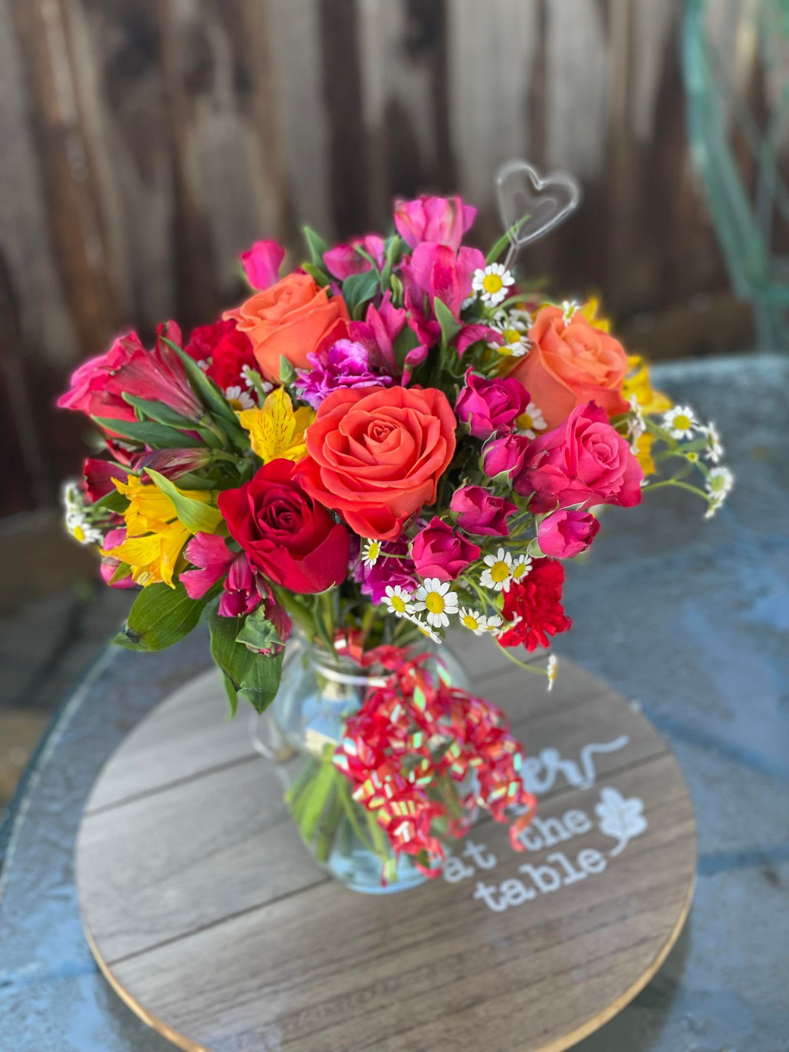 Mixed bouquet of roses and bright flowers in a glass vase