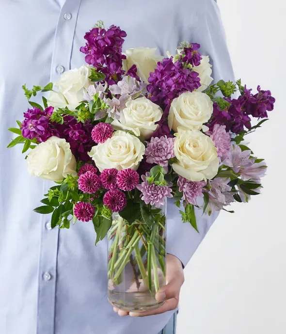 Bouquet of white roses and purple flowers in a glass vase