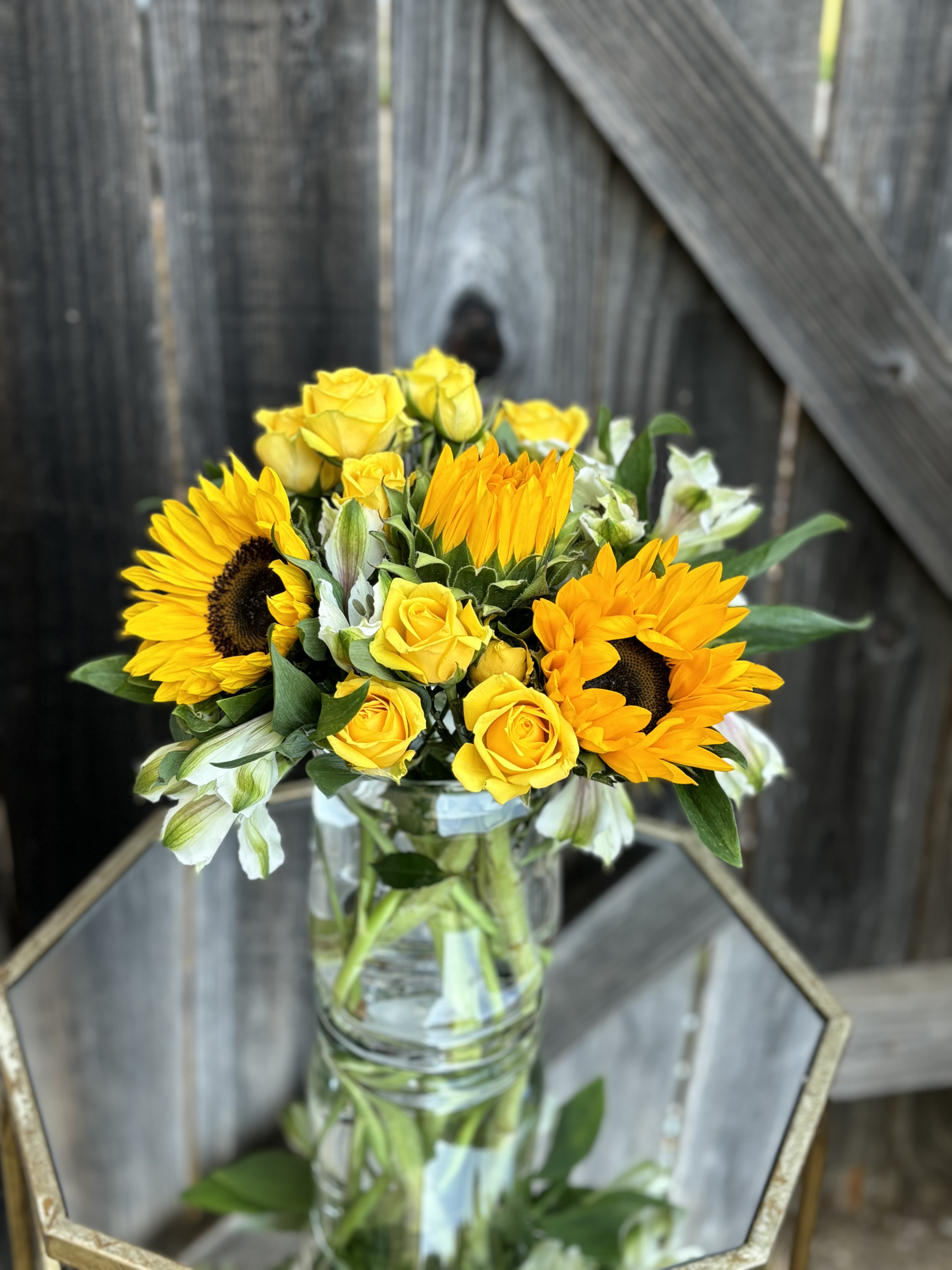 Yellow sunflowers and roses in a clear glass vase