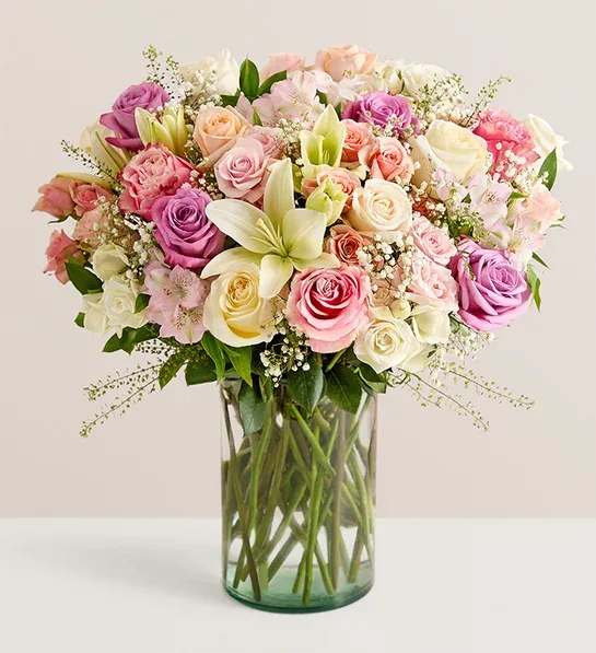 Mixed pastel bouquet of roses and lilies in a clear glass vase