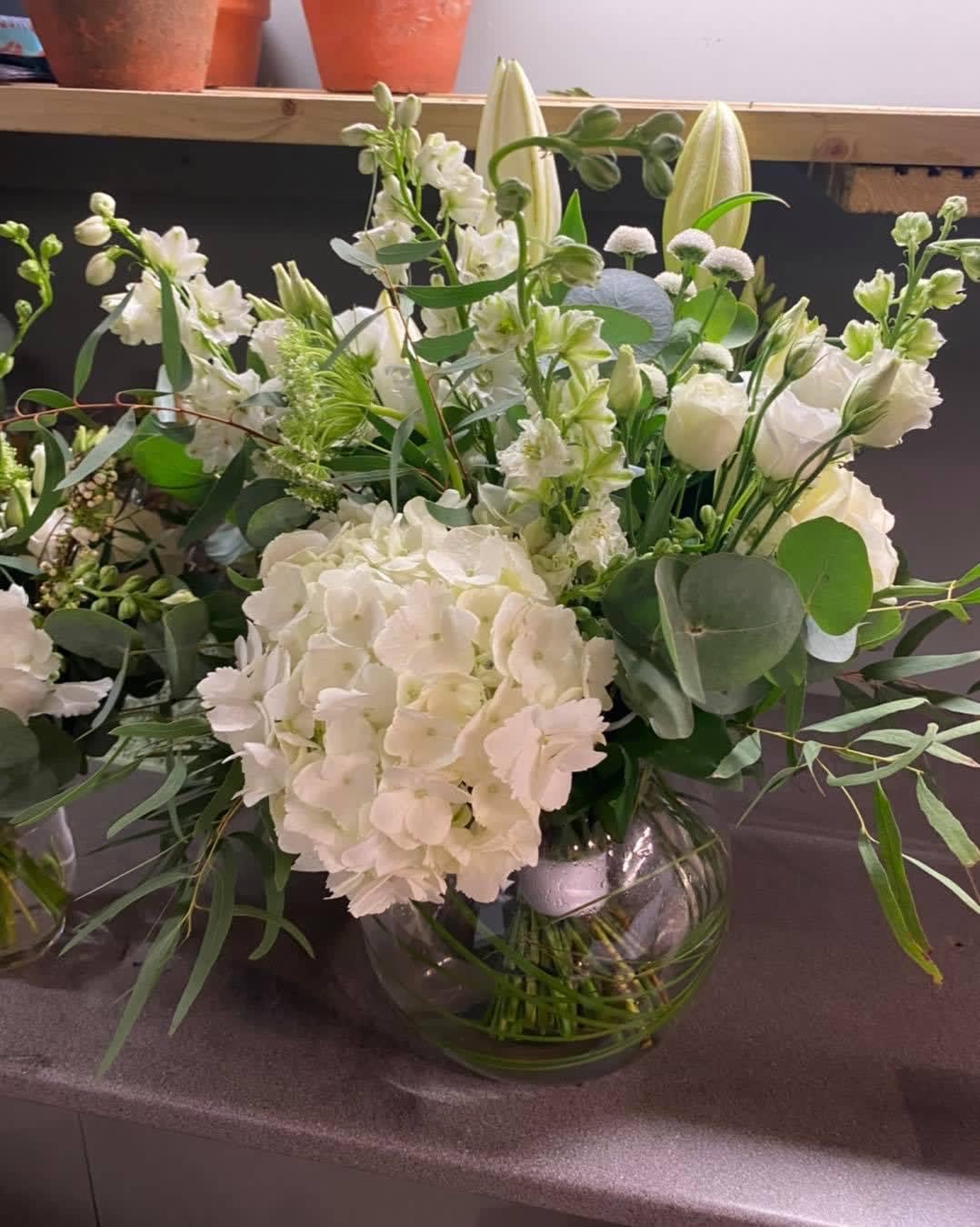 White floral arrangement in a clear glass vase with mixed greenery