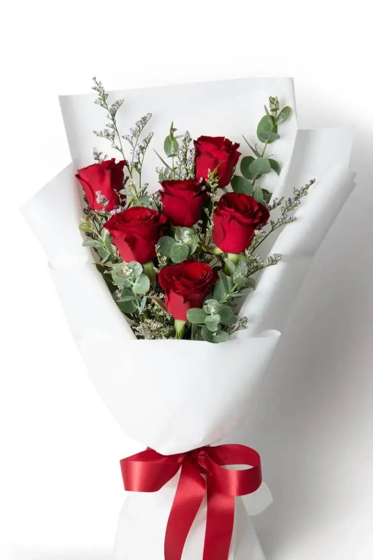 Bouquet of red roses wrapped in white paper with a red ribbon