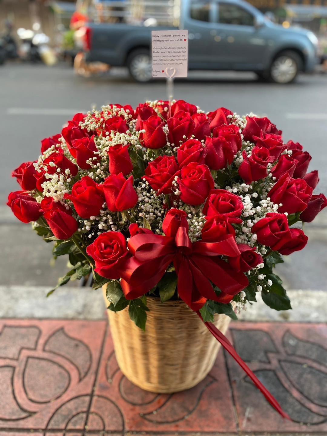 Basket of red roses with baby's breath and a red ribbon bow