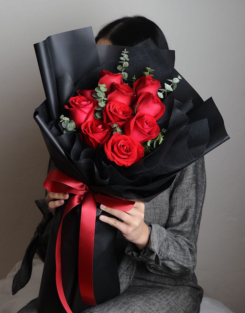 Bouquet of red roses wrapped in black paper with a red ribbon