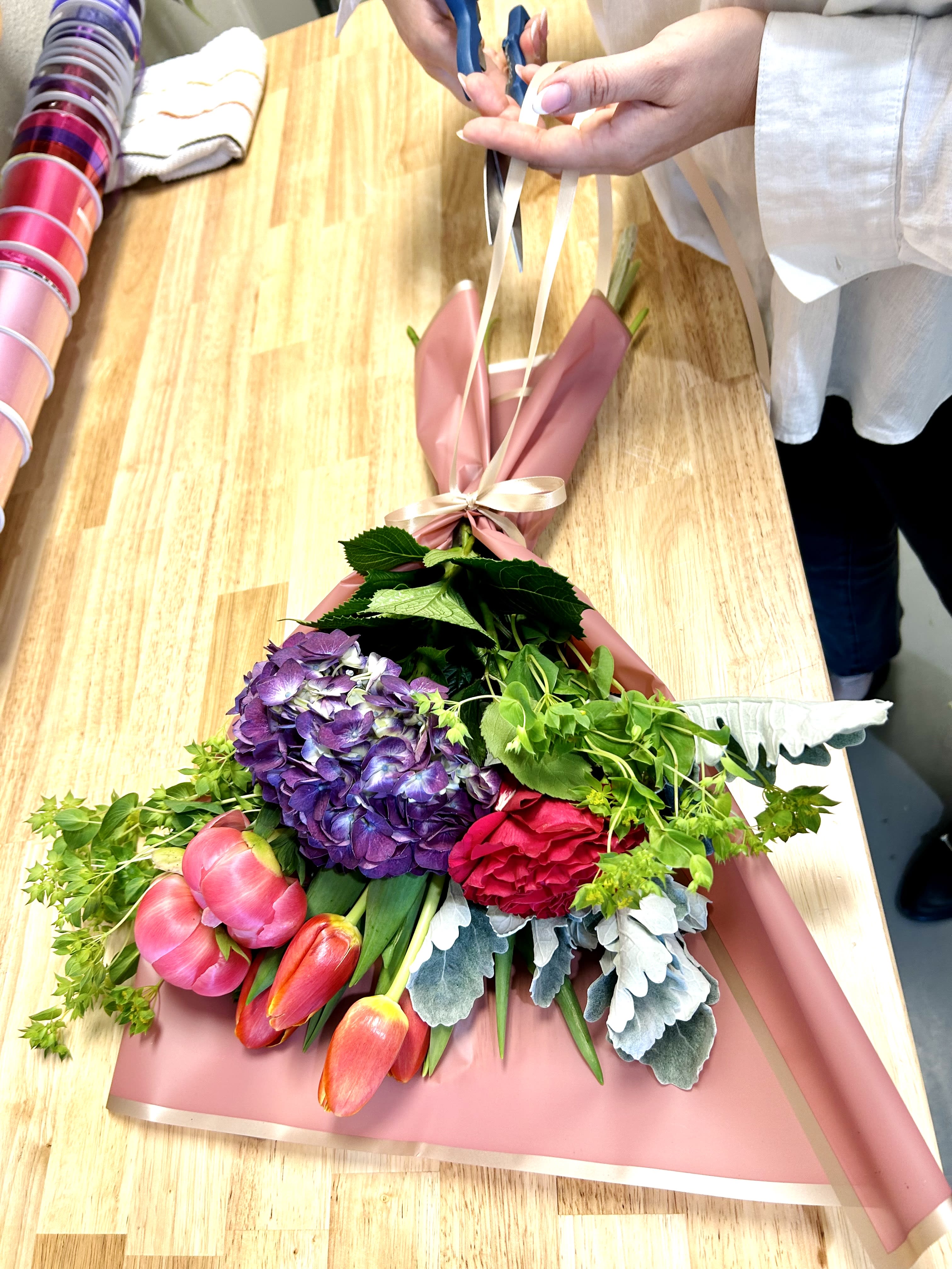 Bouquet of purple hydrangea, pink tulips, and a red rose wrapped in pink paper