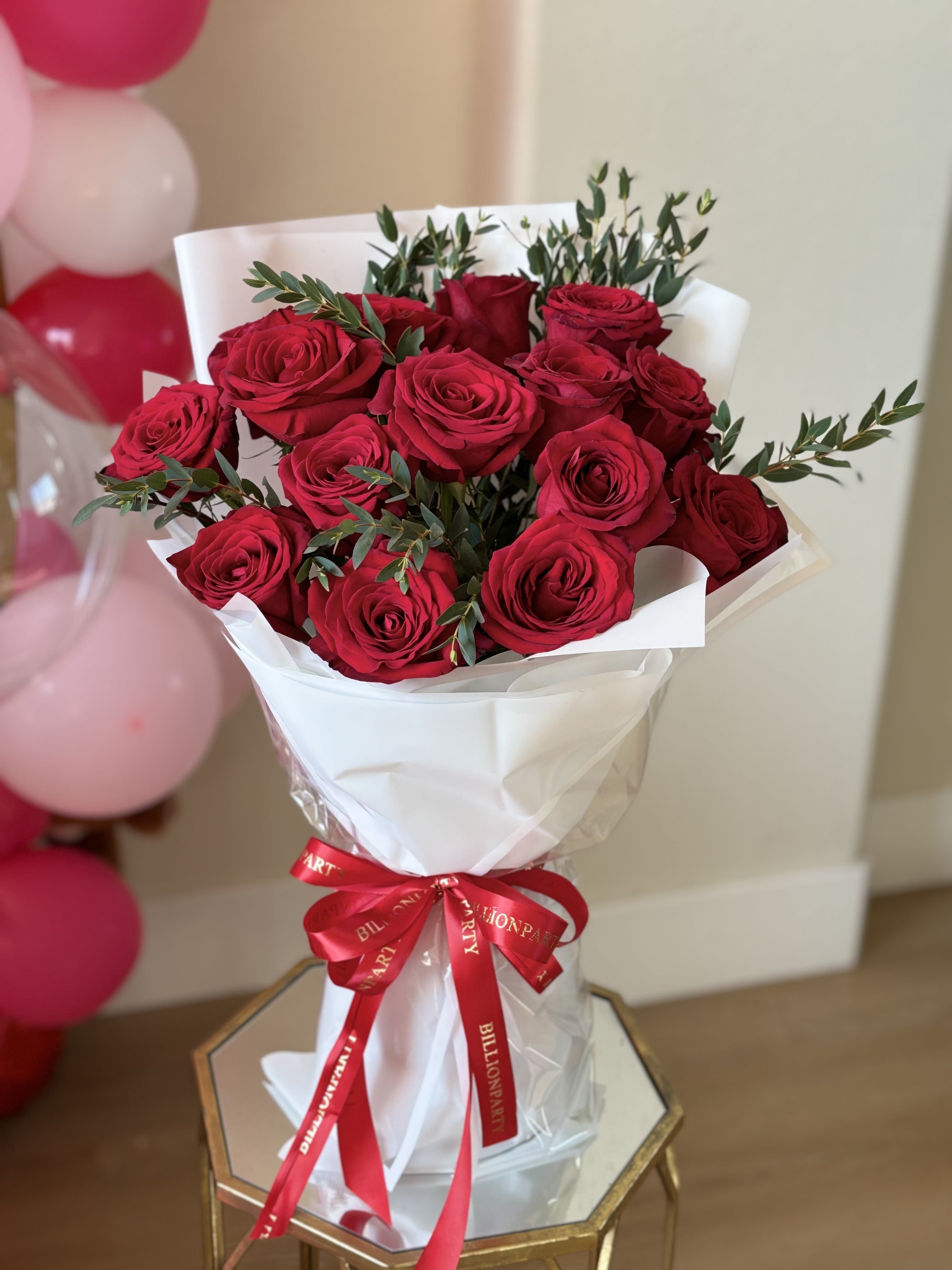 Bouquet of red roses wrapped in white paper with a red ribbon
