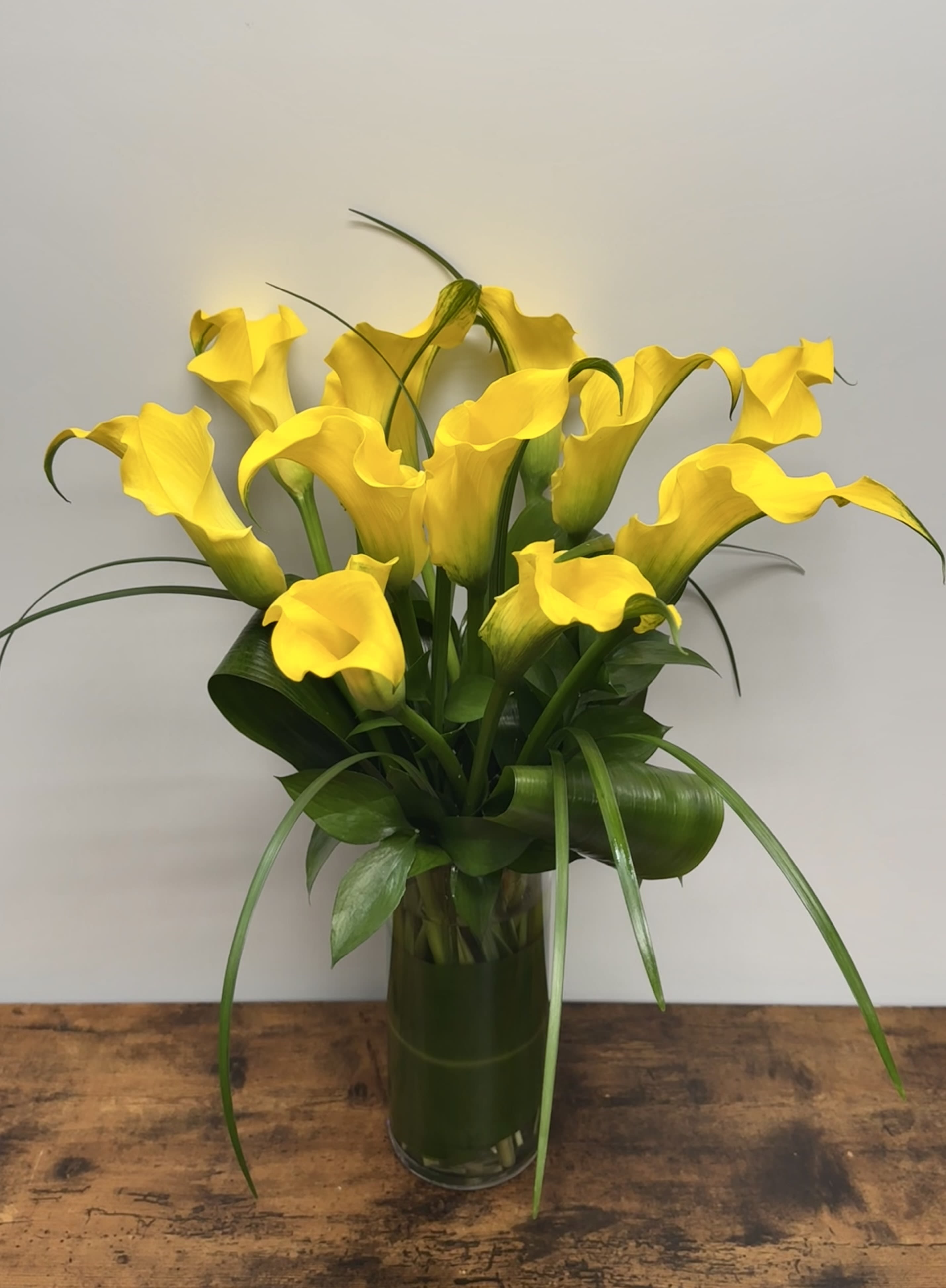 Yellow calla lilies arranged in a clear glass vase