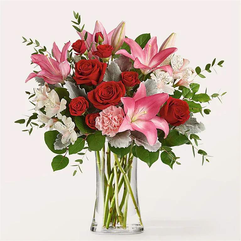Pink lilies and red roses in a clear glass vase