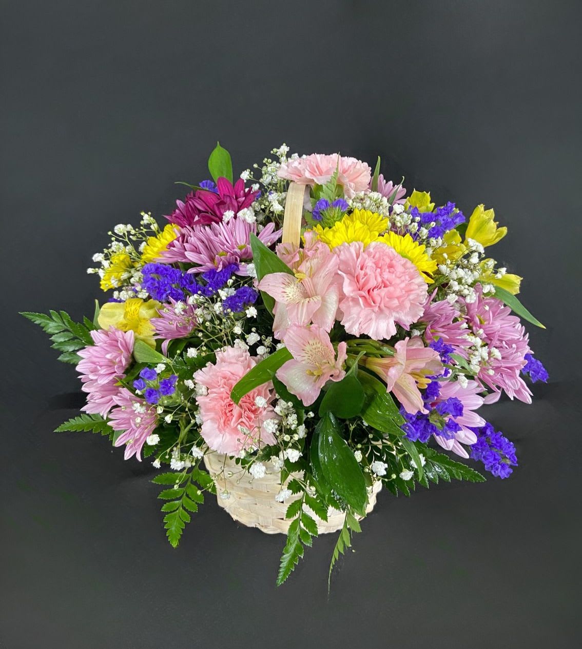 Basket of Cheer - A basket of bright, colorful flowers to pick up anyone's spirits. Includes Daisies, Carnations, Alstro, and seasonal filler flowers.