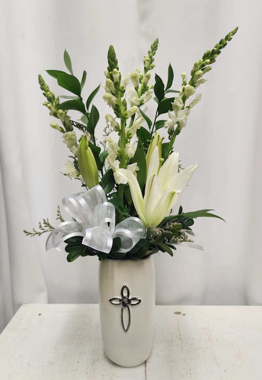 White lilies and snapdragons in a tall vase with a silver ribbon bow