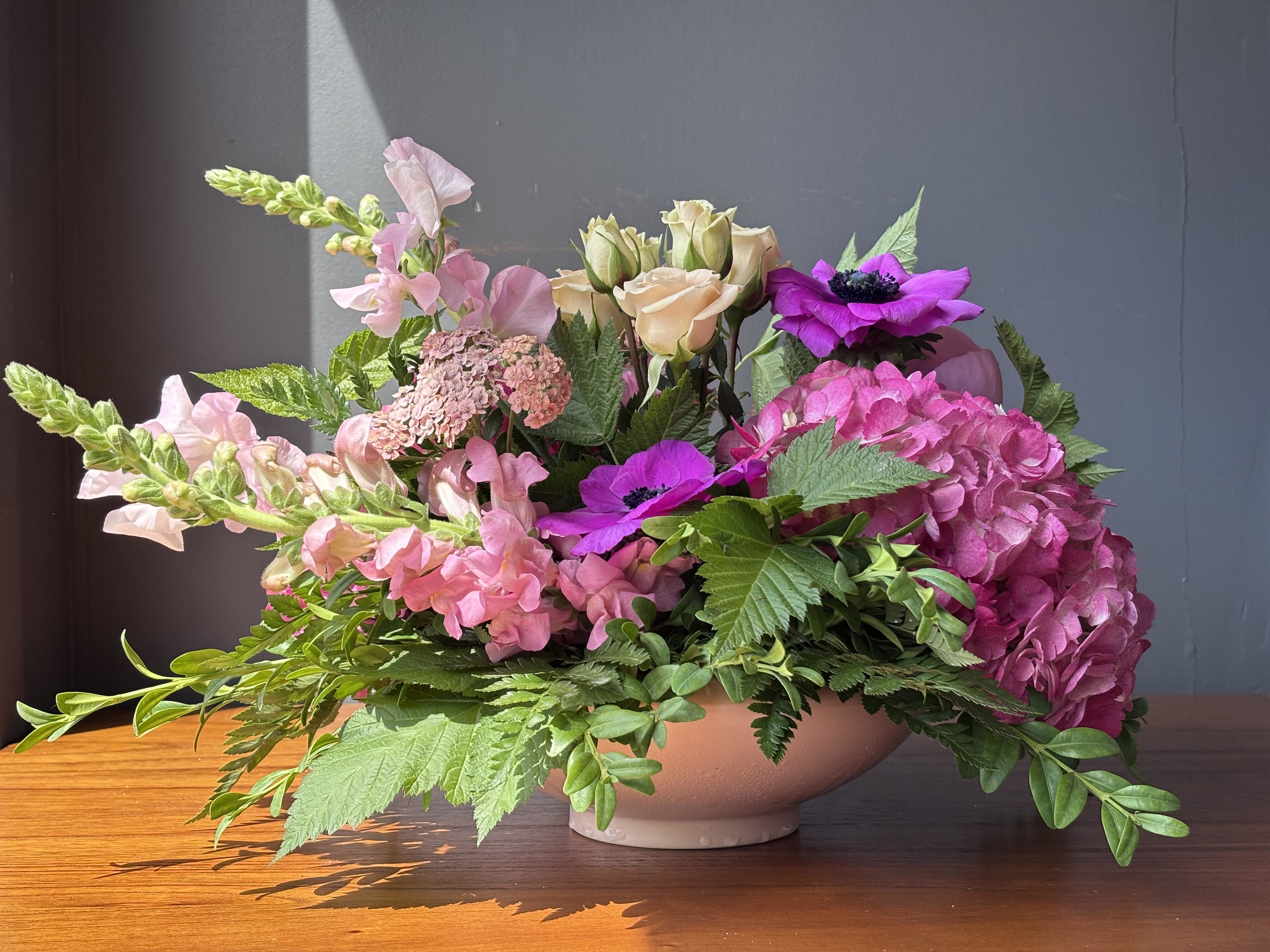 Pink and purple floral arrangement in a low bowl vase