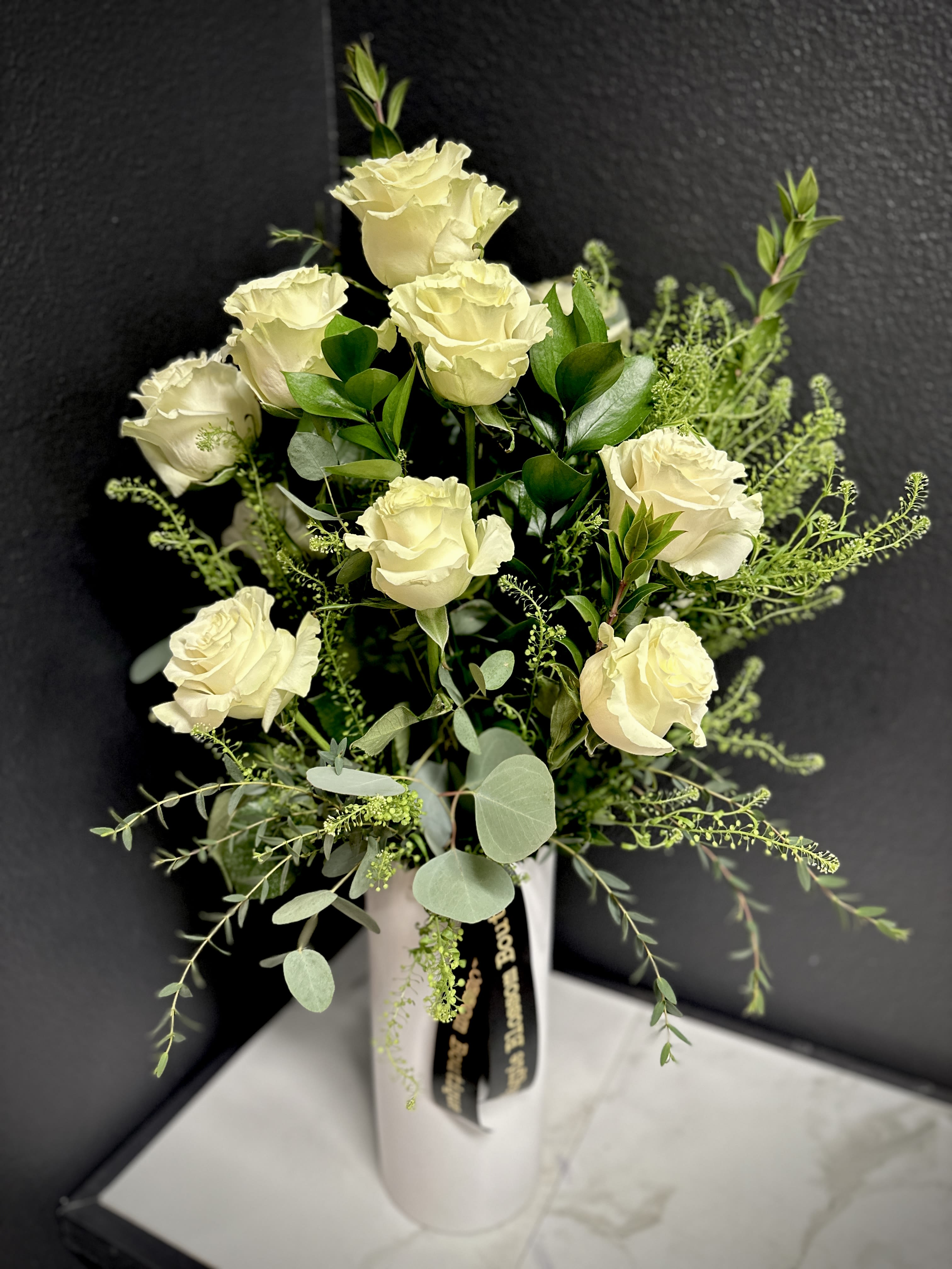 Cream roses in a white vase with airy greenery