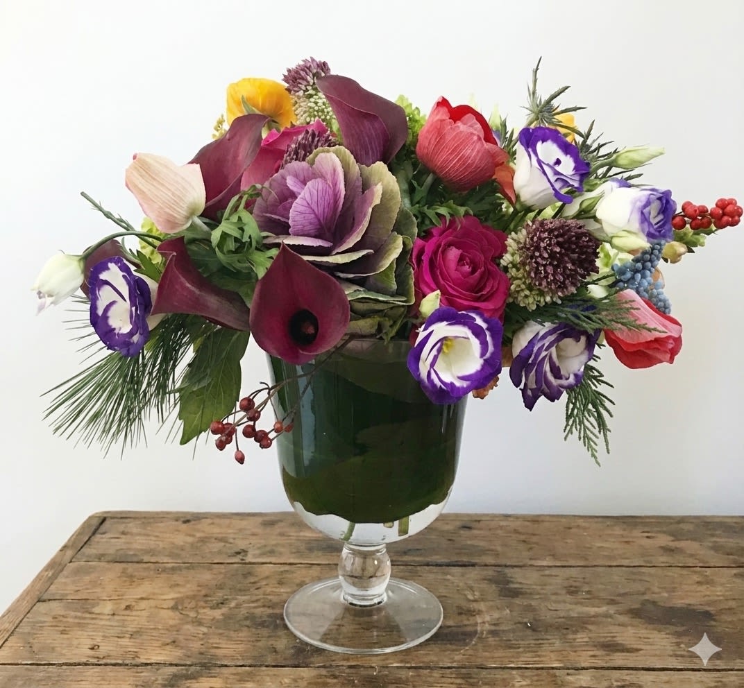 Festive - This arrangement are presented in a clear pedestal vase. It's a very merry, very festive design. The design picked purple bio-color lisanthus, green hydrangea, allium, hot pink roses, purple kale, red anemone, purple calla, yellow ranunculus, mascara, and assorted holiday greens. 