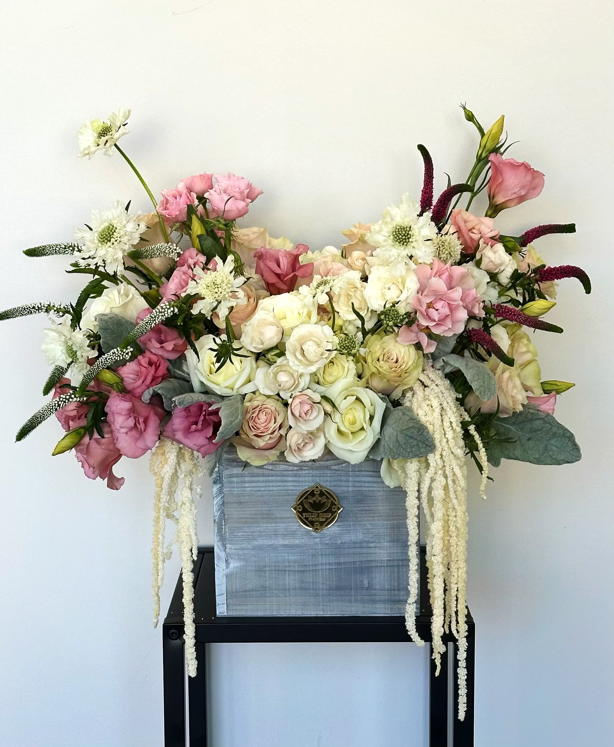 Large pastel floral arrangement in a blue box with trailing white blooms