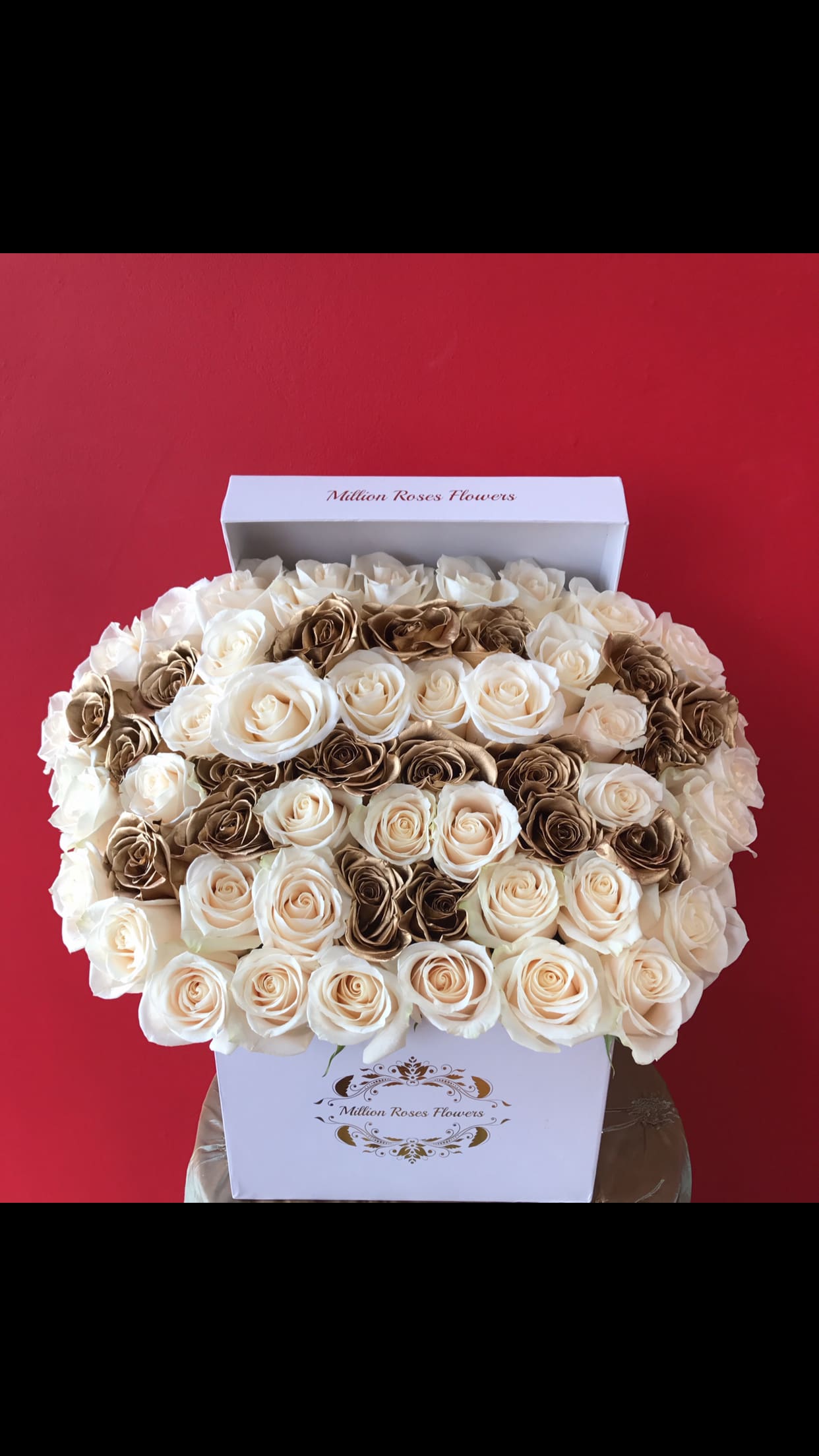 Boxed arrangement of cream and brown roses against a red background