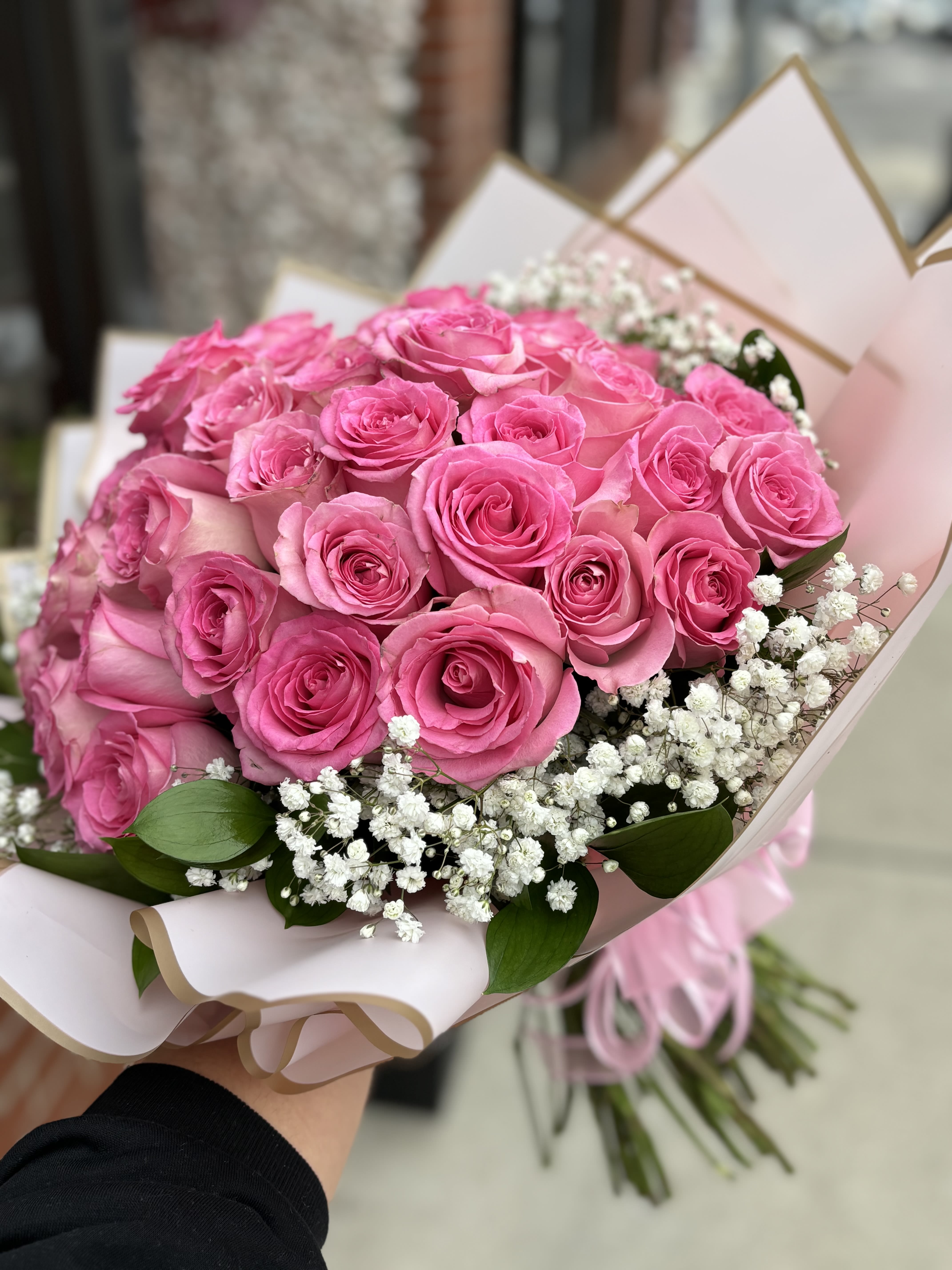 Bouquet of pink roses with white baby's breath in pale pink wrap