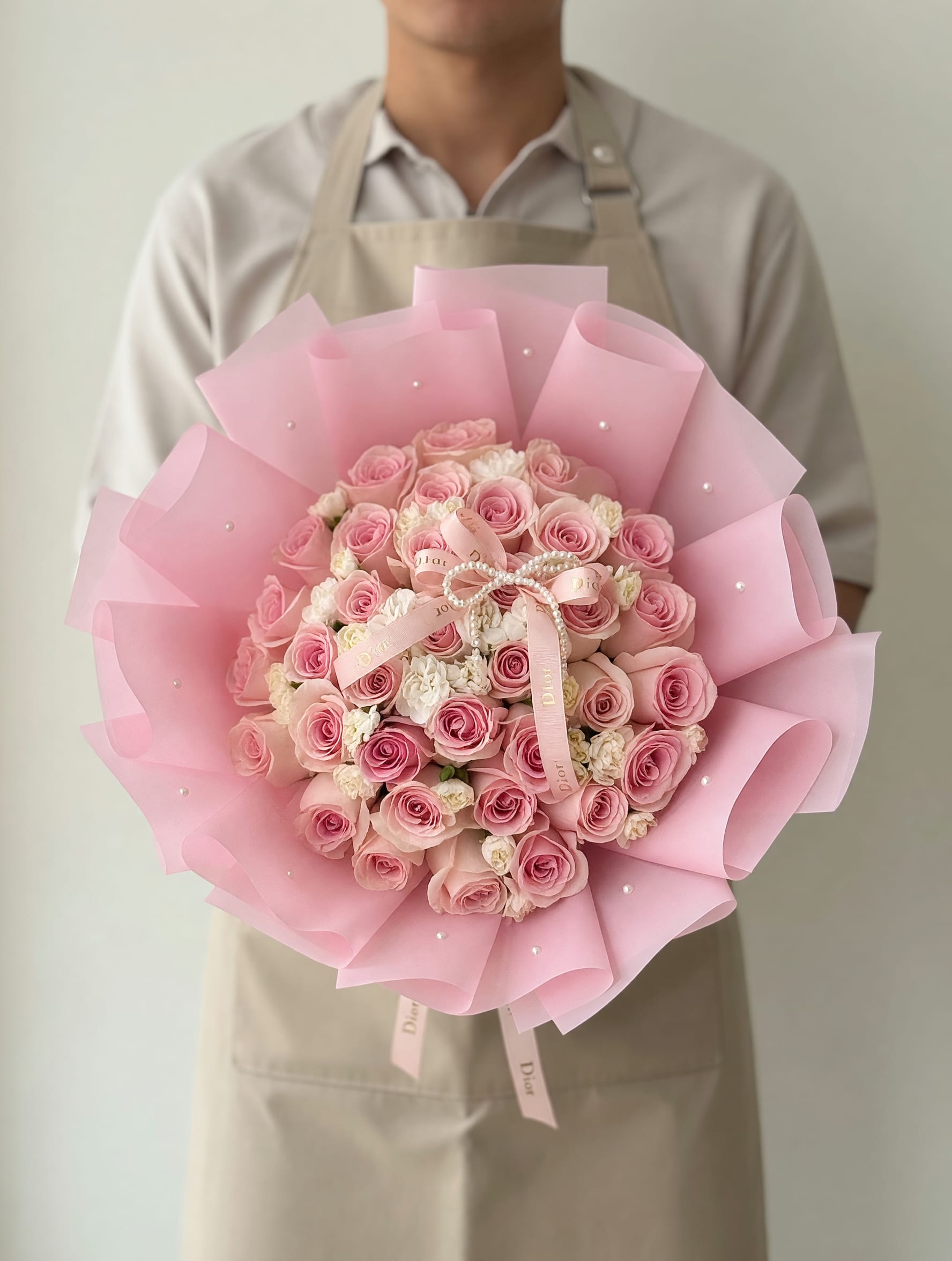 Blush Pearl Elegance Bouquet - A luxurious bouquet featuring delicate blush pink roses and soft white accent blooms, beautifully arranged in a full round shape and wrapped in elegant pastel layers with pearl details and a refined ribbon finish. Blush Pearl Elegance is designed to express grace, sophistication, and timeless beauty—perfect for unforgettable moments.