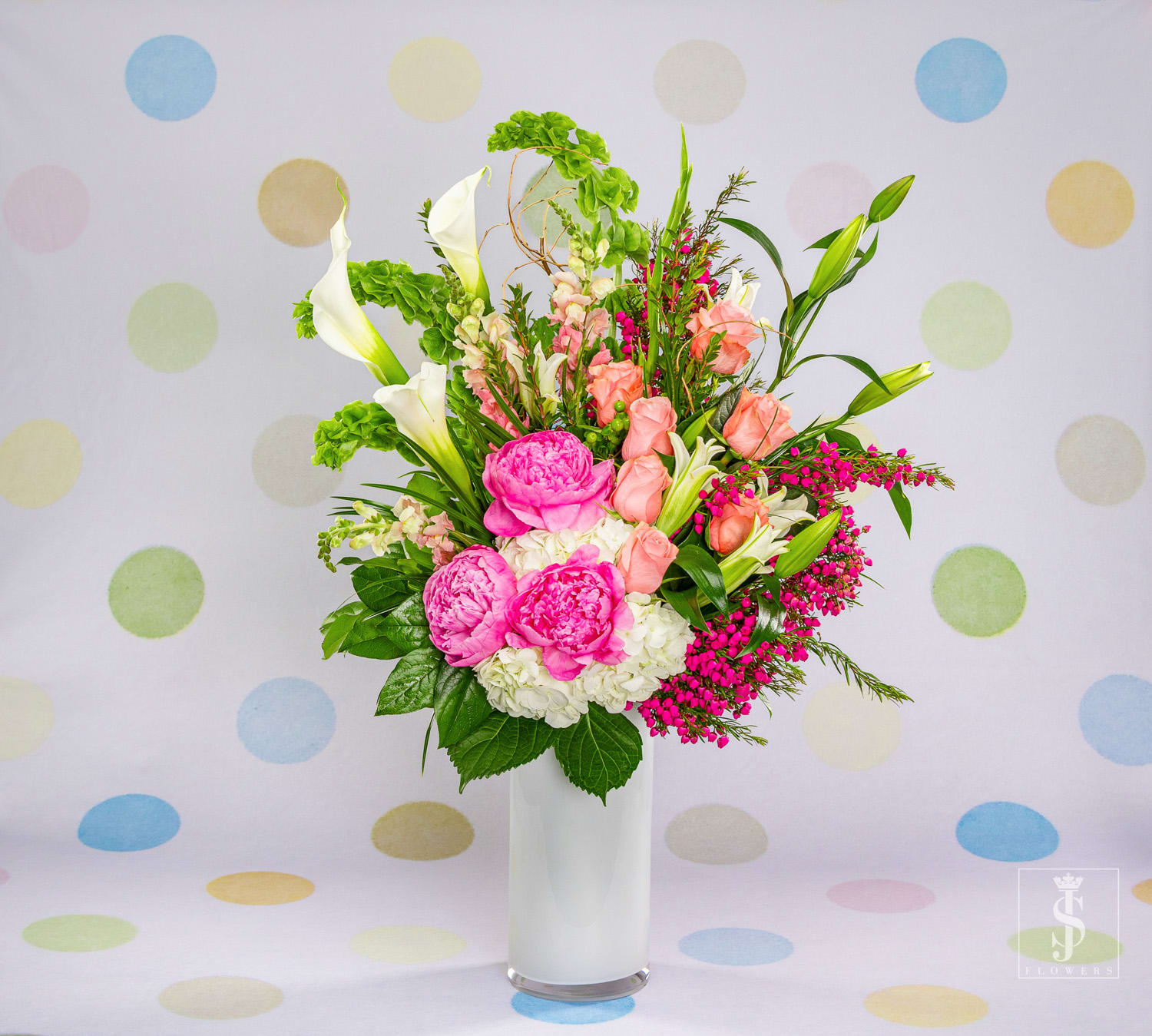 Exquisite Peony  - Exquisite Peony is a stunning multifaceted work of art, each angle looks as if it is a different arrangement. The peachy, blush and pink hues are comprised of Peonies , Lilies , Calla Lilies  and Roses, green Bells of Ireland, and White Hydrangeas. This elegant and enchanting arrangement stands at 22 inches tall with a width of 14 inches. 