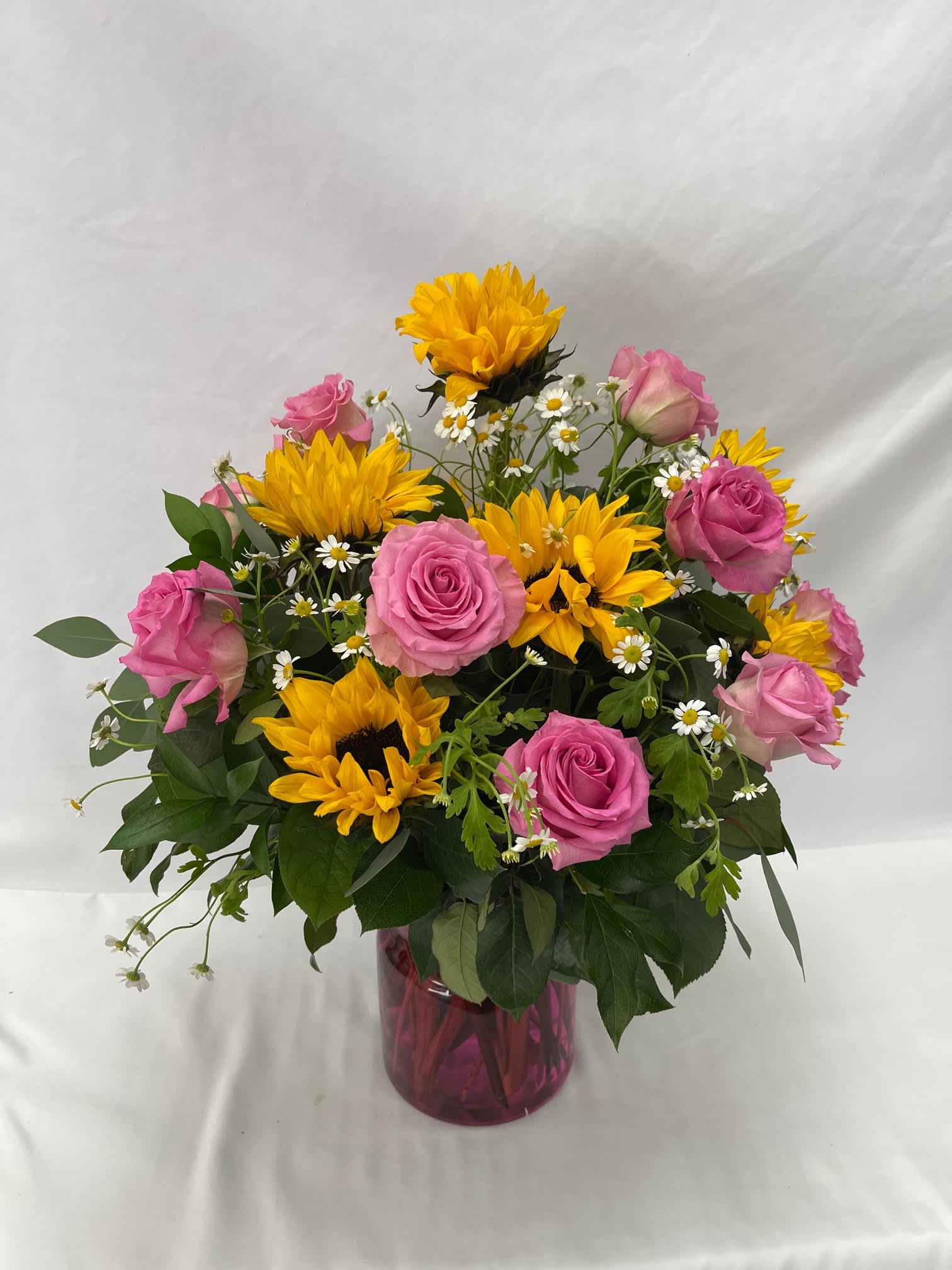 Pink Charms - Select this beautiful and bright arrangement featuring pink roses, sun flowers, and chamomile.  Filler flower may vary