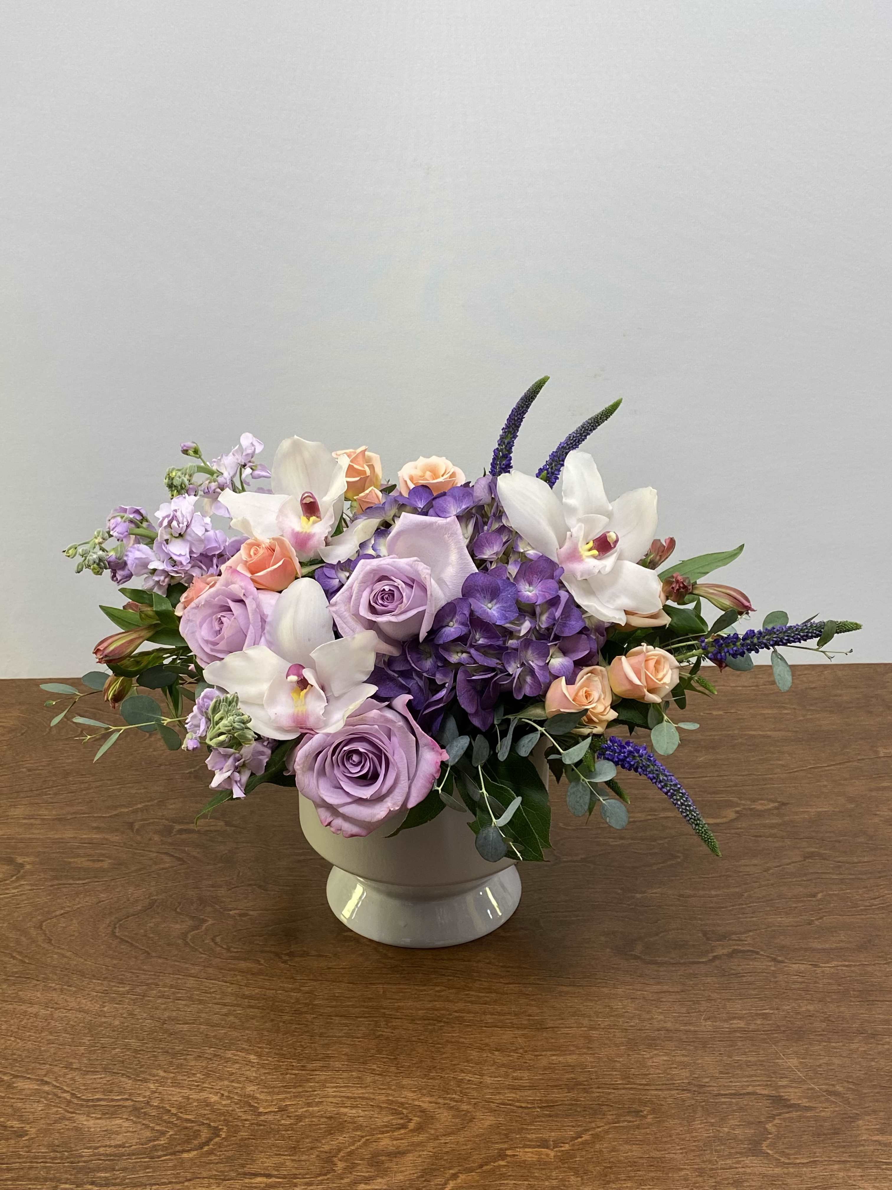 Blooming Delight - A soft and elegant composition designed to feel both fresh and refined, Blooming Delight features a beautiful blend of hydrangea, cymbidium orchids, roses and spray roses, accented with the delicate fragrance of stock and the graceful movement of veronica. Arranged in a high-end lavender ceramic container, this piece brings together texture, color, and luxury in perfect balance. The result is a sophisticated garden-style arrangement that feels abundant, polished, and effortlessly beautiful—perfect for celebrating Mother’s Day or elevating any meaningful moment.