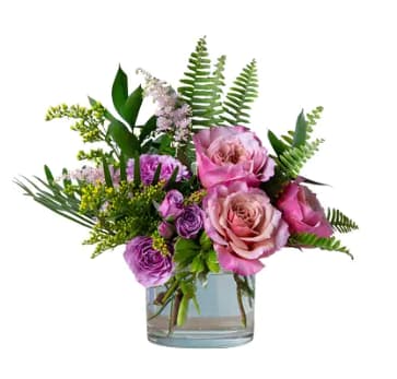 Pink and purple roses arranged in a clear glass vase
