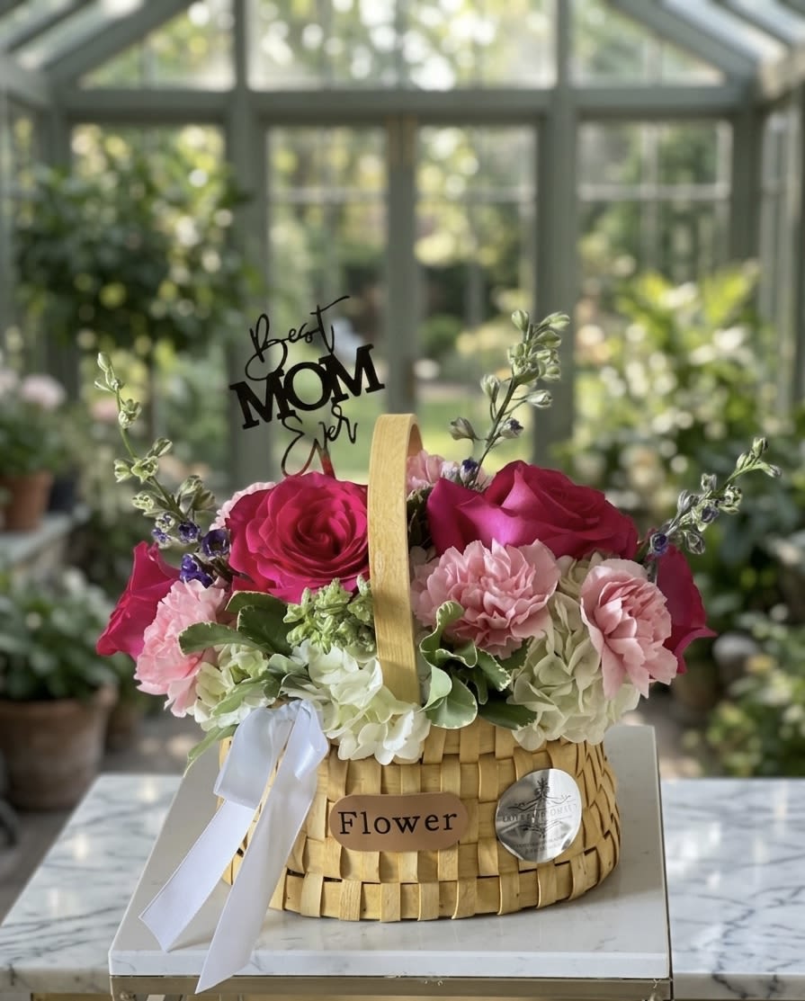 Basket for Mom  - Celebrate the special women in your life with this elegant, artisanal floral arrangement. Hand-crafted in a charming woven basket, this display features a vibrant blend of deep magenta roses, soft pink carnations, and lush white hydrangeas. Accented with delicate greenery and a "Best Mom Ever" topper, it is the perfect centerpiece to show your appreciation. • Premium Blooms: Features high-quality roses and seasonal hydrangeas. • Ready to Display: Comes in a reusable woven basket with a satin ribbon finish. • Thoughtful Design: Includes a decorative topper to make the occasion extra special.