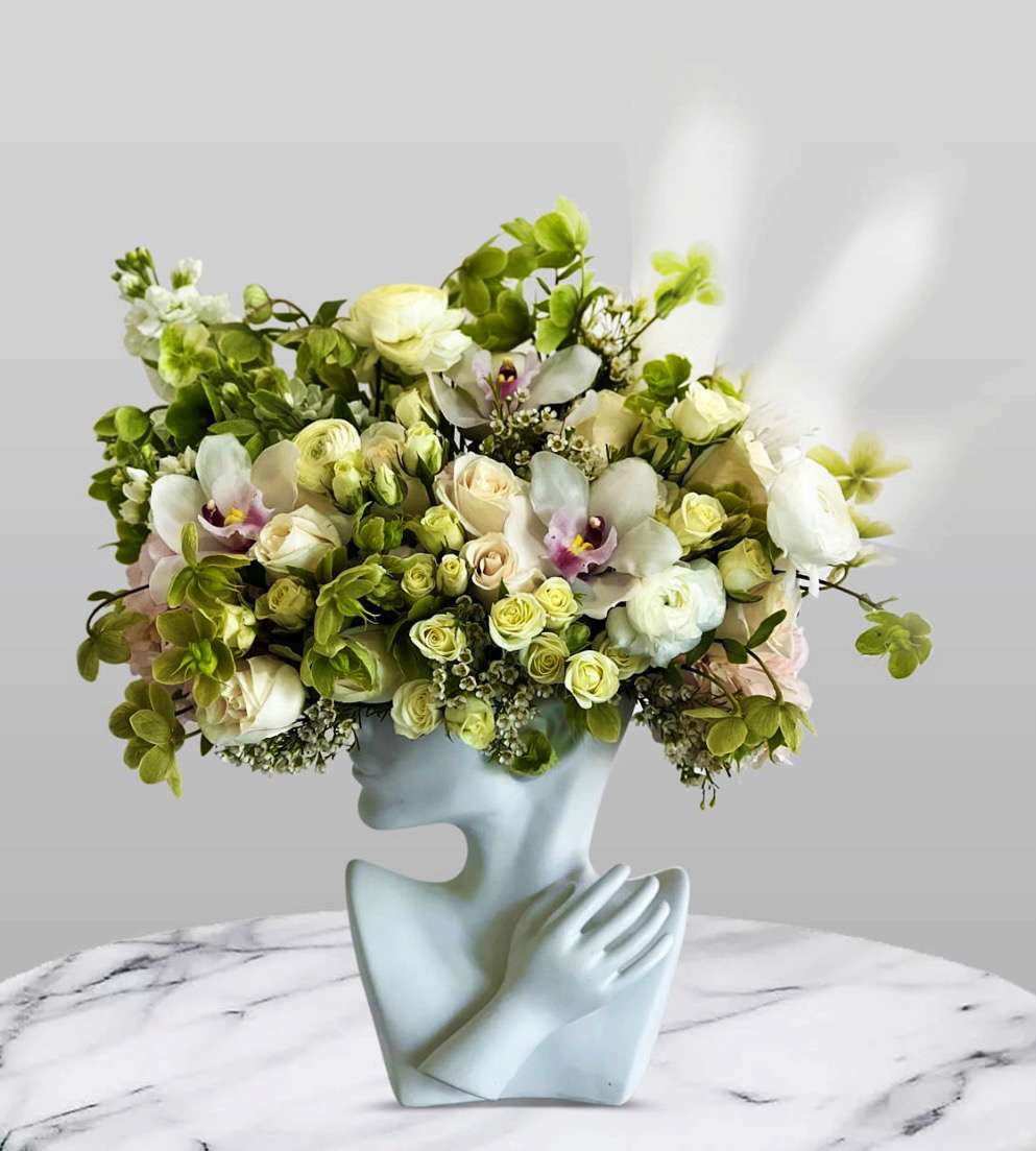 Bouquet of white and pale green flowers in a sculptural face vase