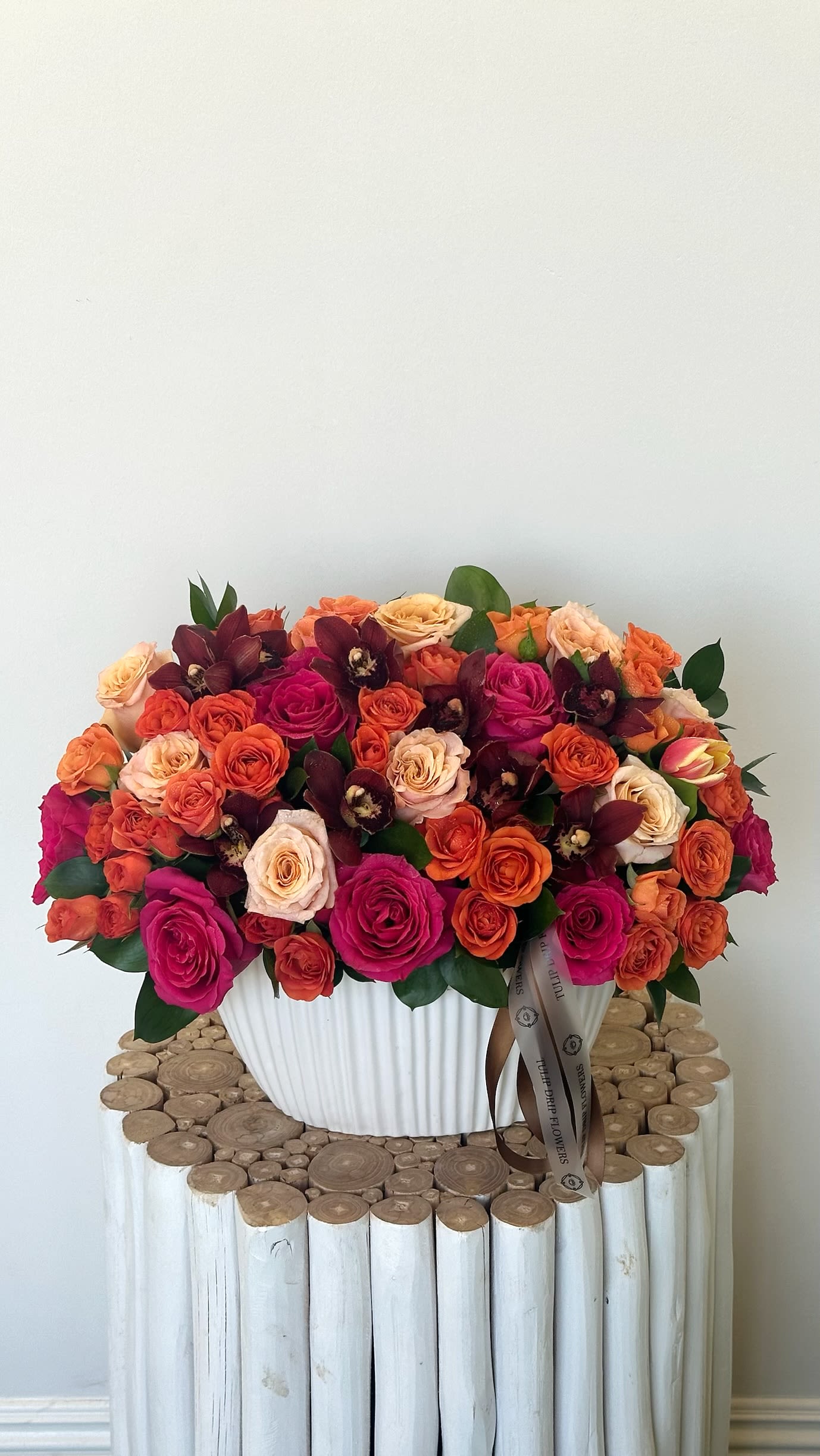 Large bouquet of pink, orange, and cream roses in a white vase