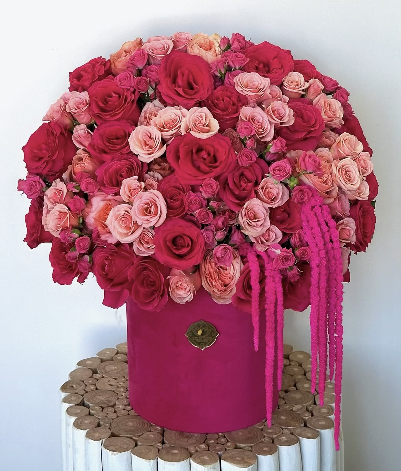 Large pink and red rose arrangement in a magenta box with trailing accents