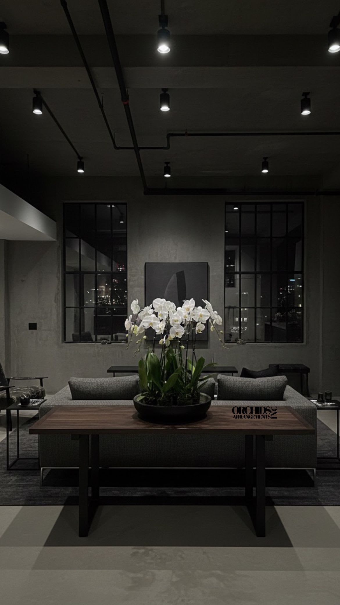 White orchids in a low black planter on a table