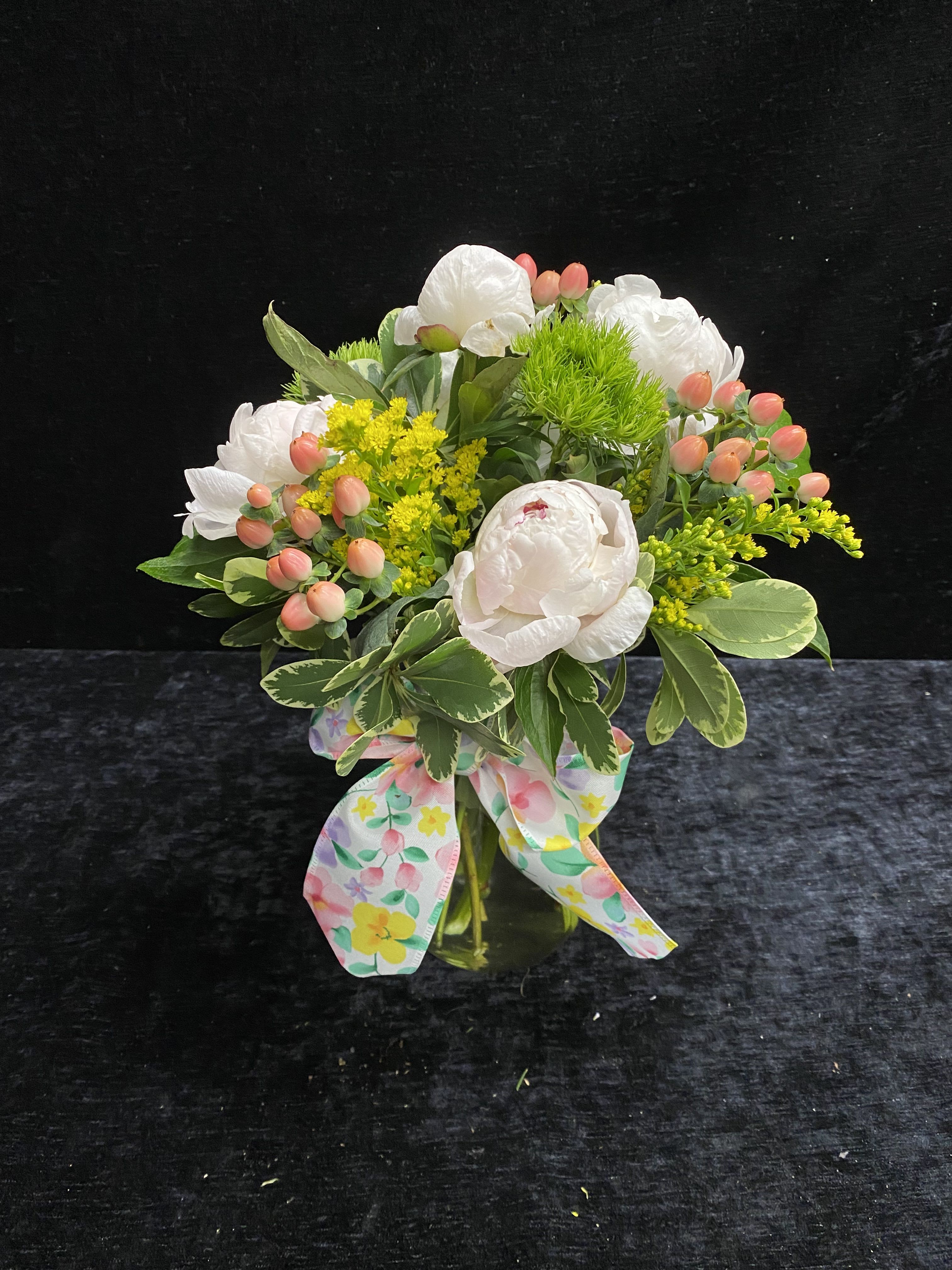Peonies Please - Peonies with hypericum berries, sunny yellow fillers and green accents in a clear glass vase, tied with a pastel ribbon. Fresh, springlike and cheerful for Mom.