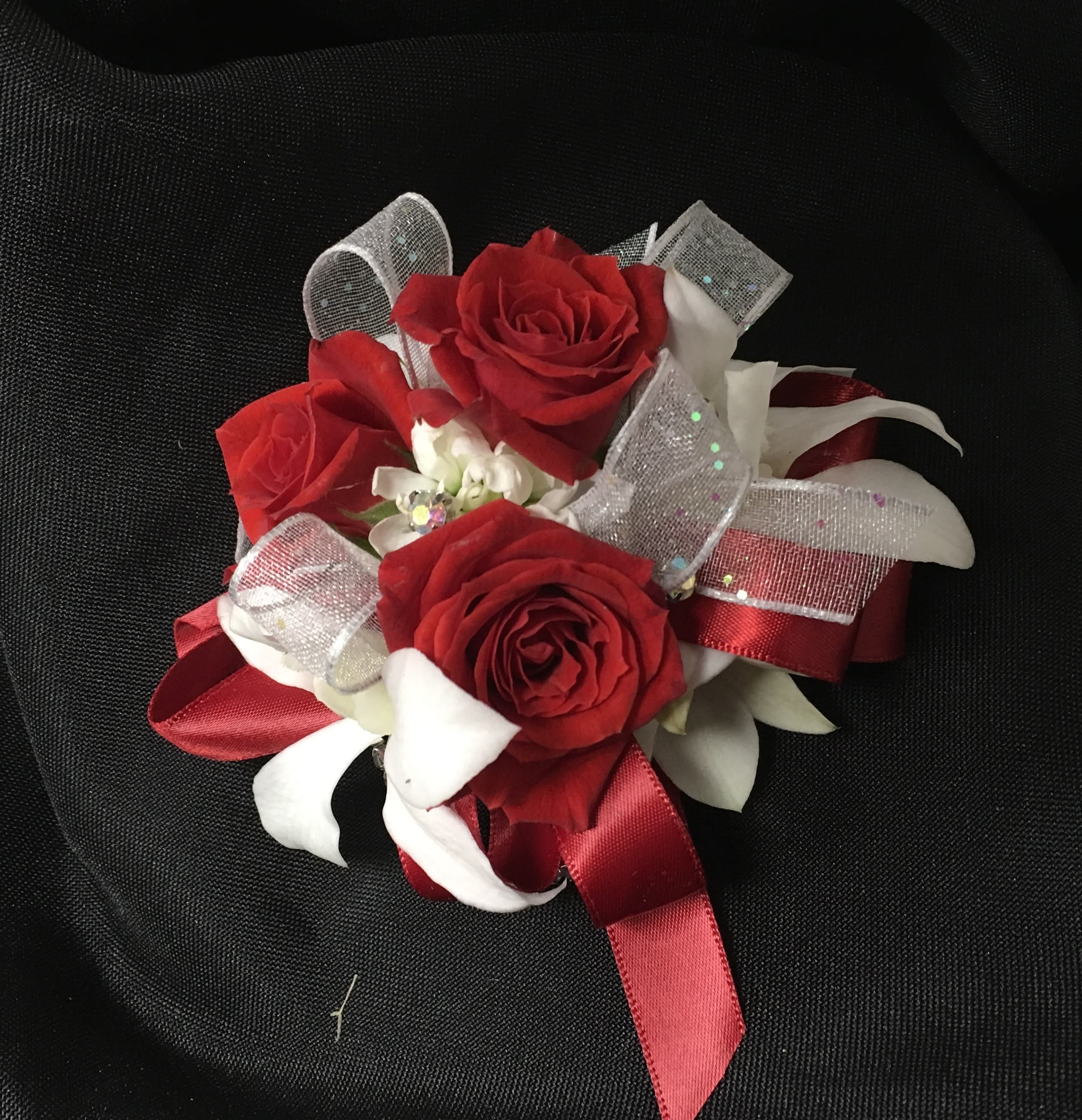 Small cluster of red roses with white ribbon accents