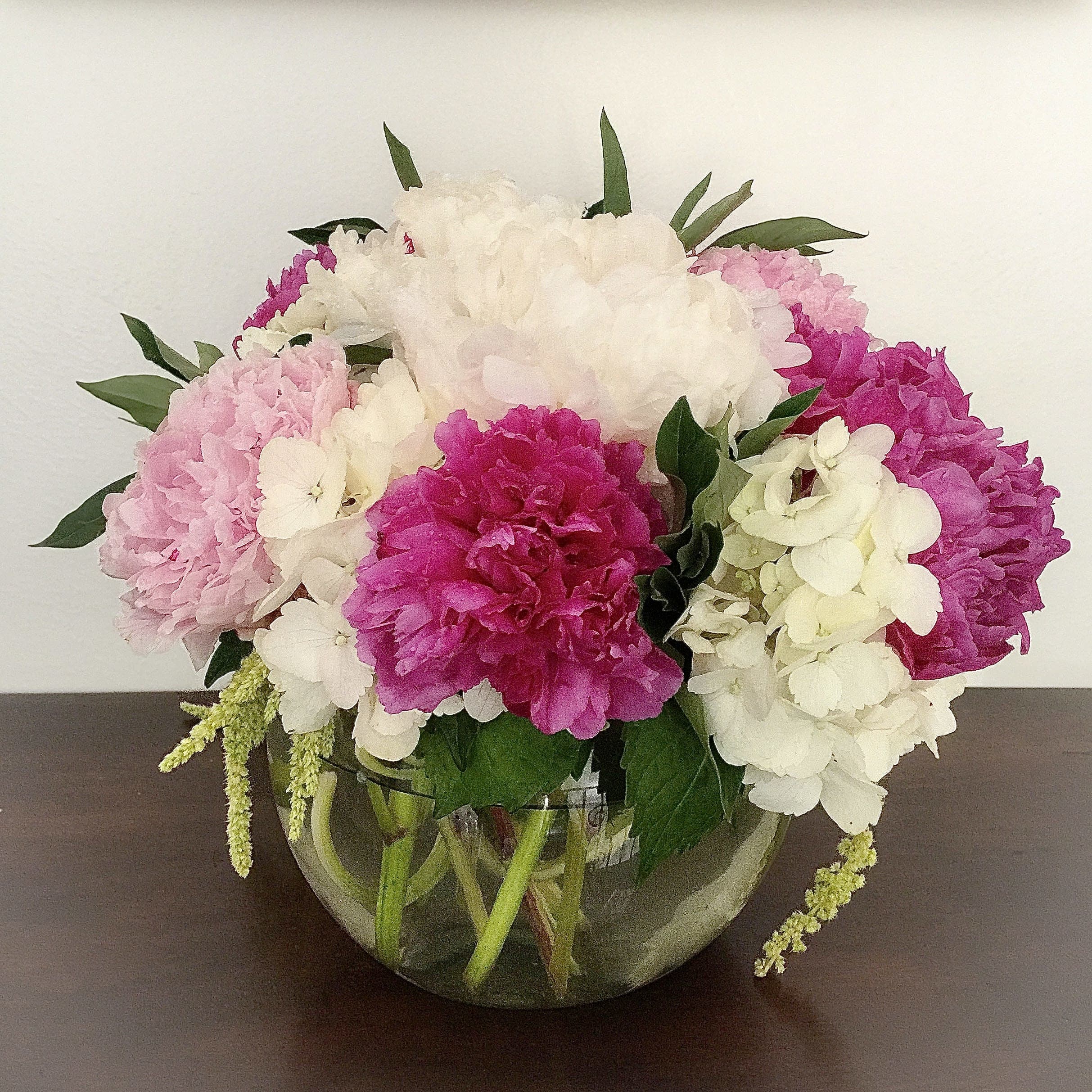 Pink and white hydrangea bouquet in a round glass vase