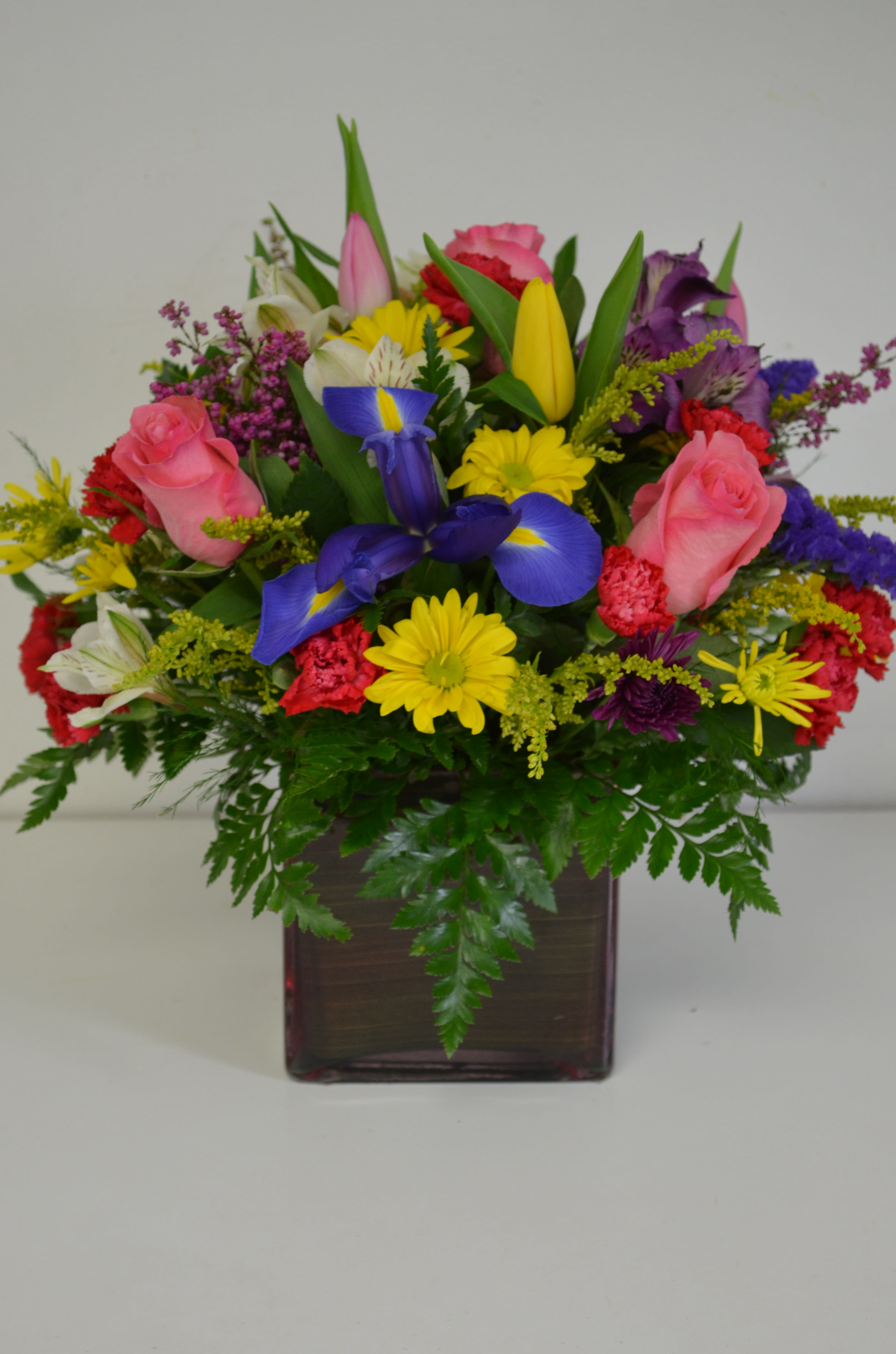 Colorful mixed flower arrangement in a square glass vase