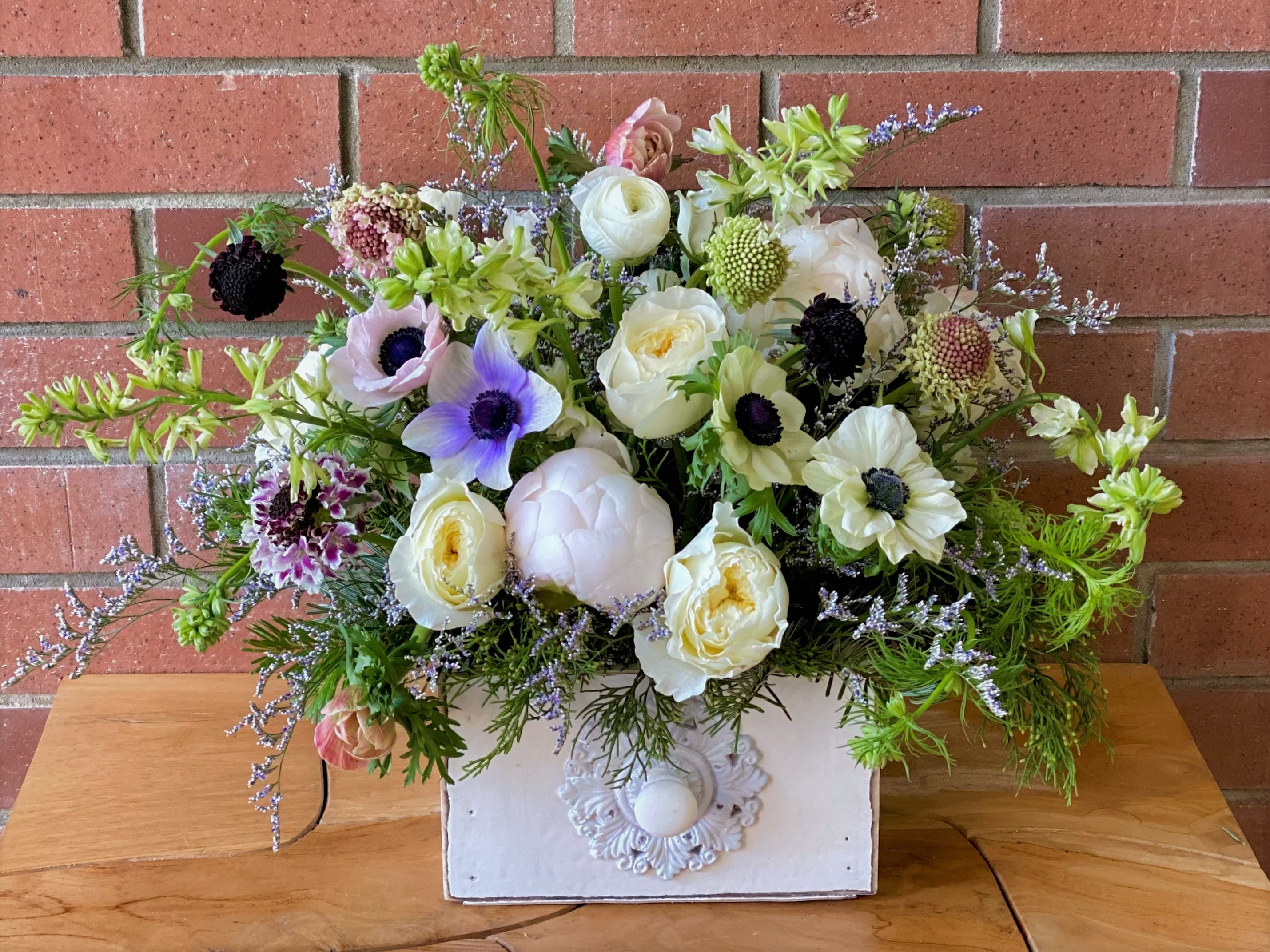 Mixed bouquet of white, lavender, and pink flowers in a white box