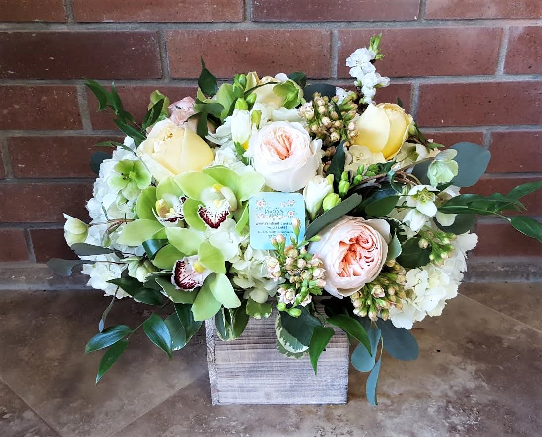 Mixed bouquet of pale roses, orchids, and white blooms in a wooden box