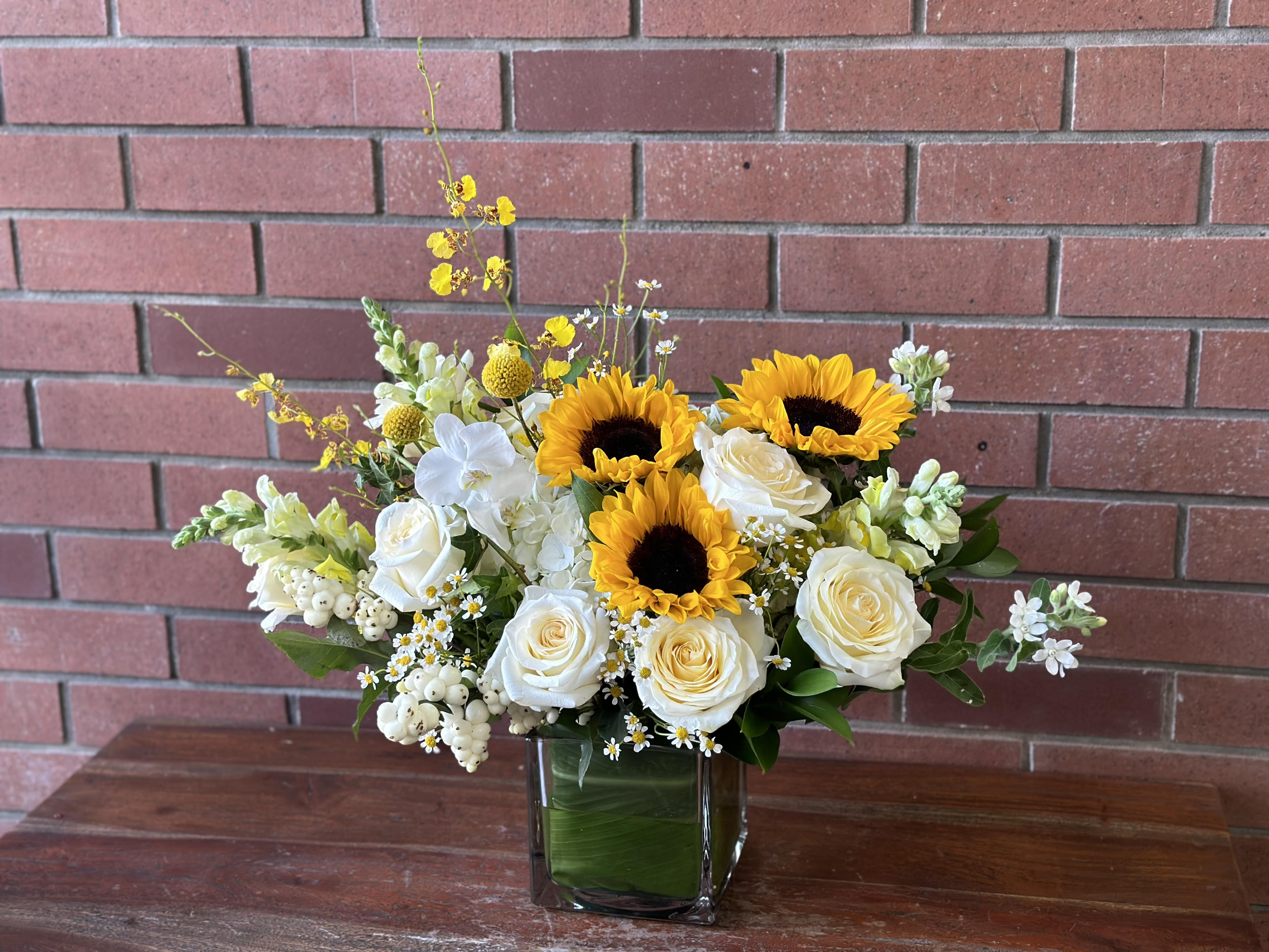 Sunflowers and white roses arranged in a square glass vase